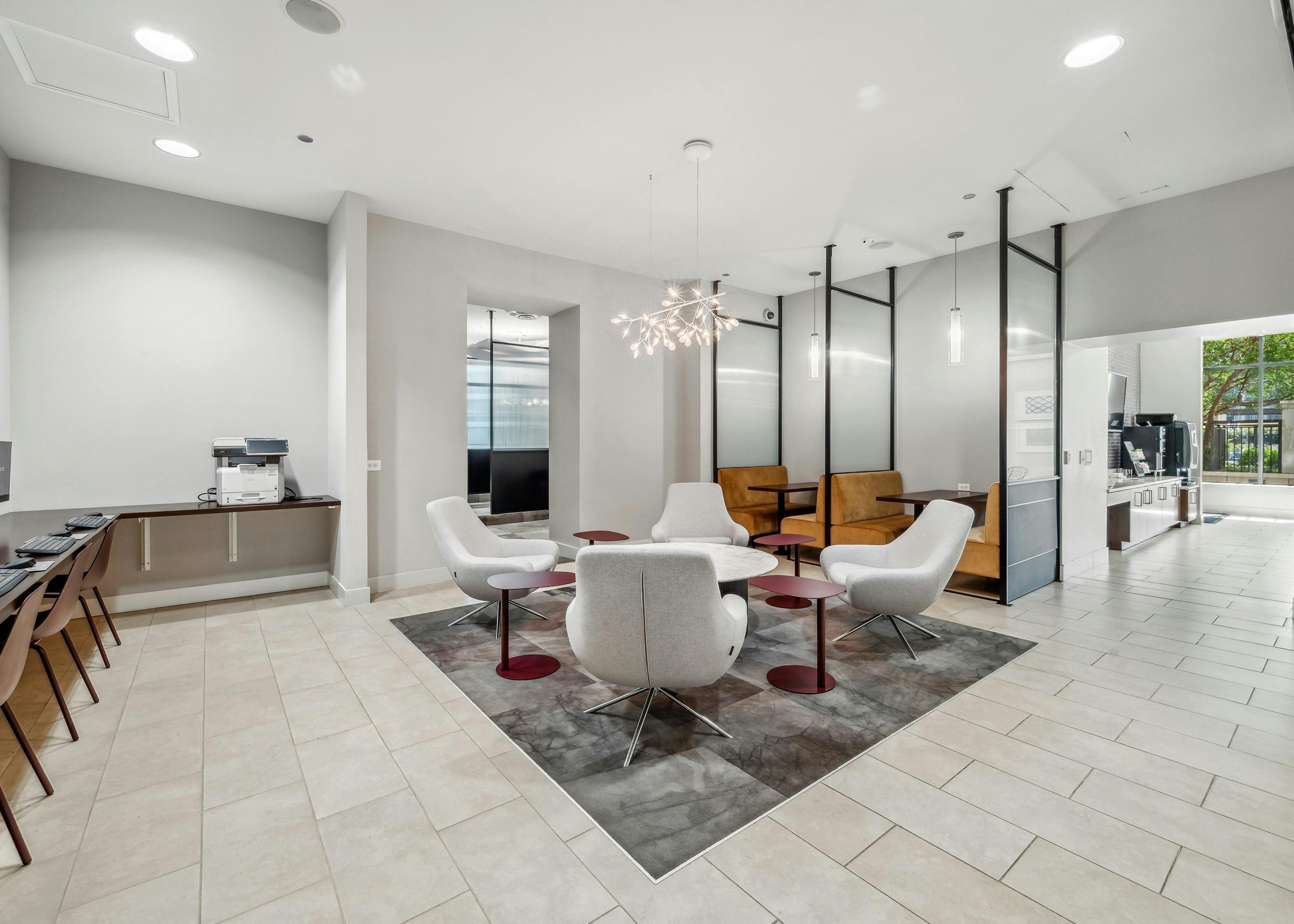 Interior view of co working space with 4 gray chairs around table and booth seating open to morning room at AMLI River North
