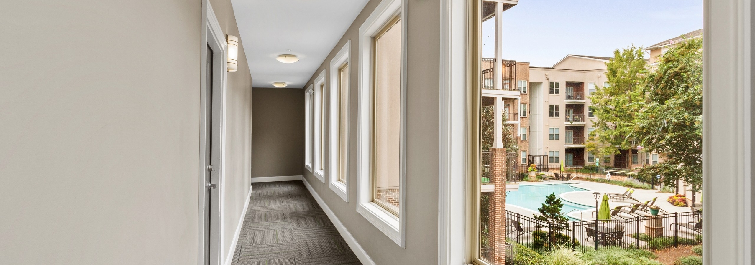 Bright breezeway leading outdoors with daytime view of pool from one of several large windowpanes at AMLI Lindbergh