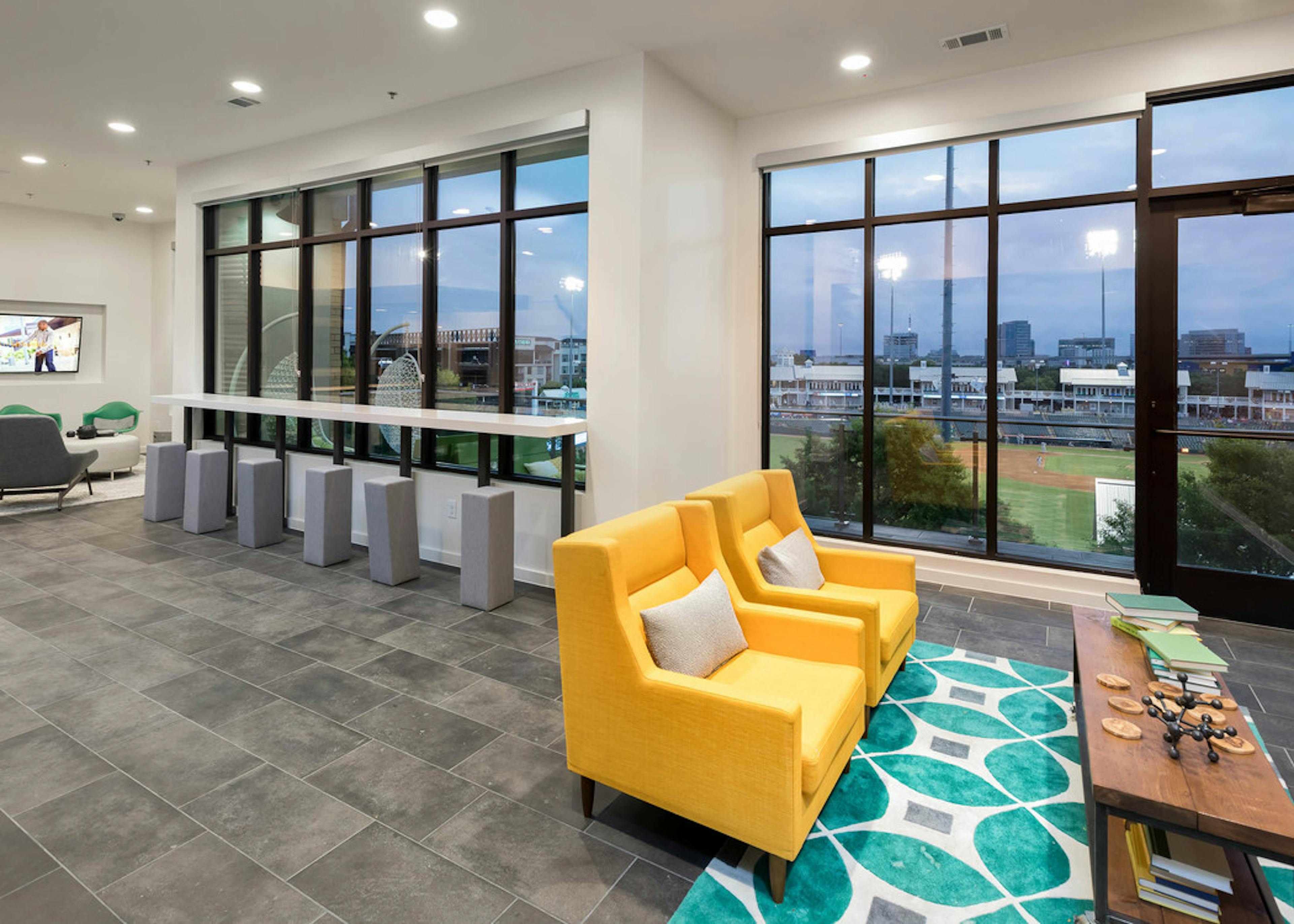 Interior view of skybox suite with seating areas overlooking Riders Field at AMLI Frisco Crossing apartment building 