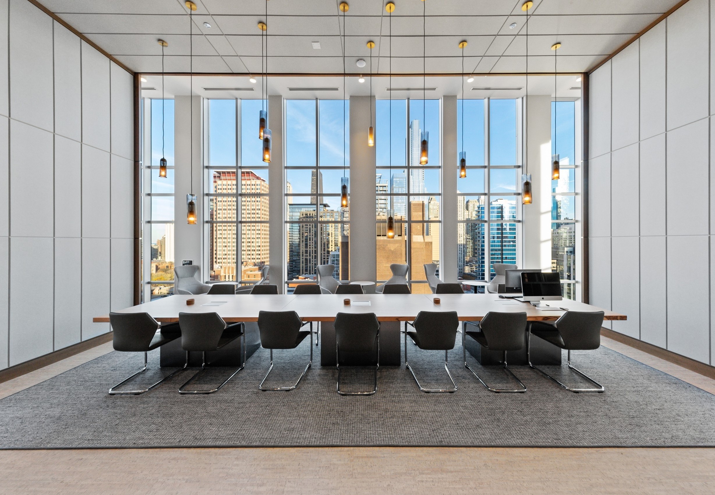 AMLI 808 conference room with pendant lights hanging over long modern conference table lined by black leather chairs