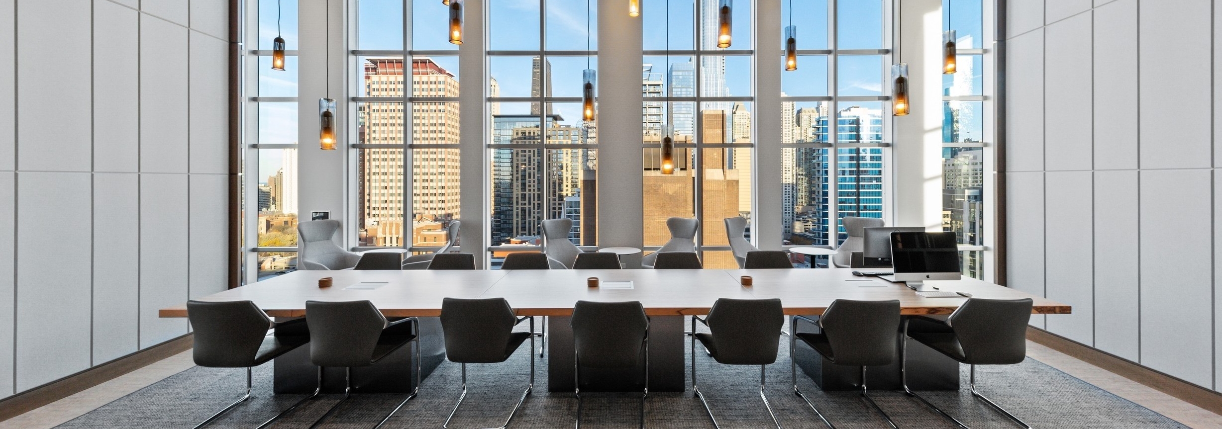 AMLI 808 conference room with pendant lights hanging over long modern conference table lined by black leather chairs