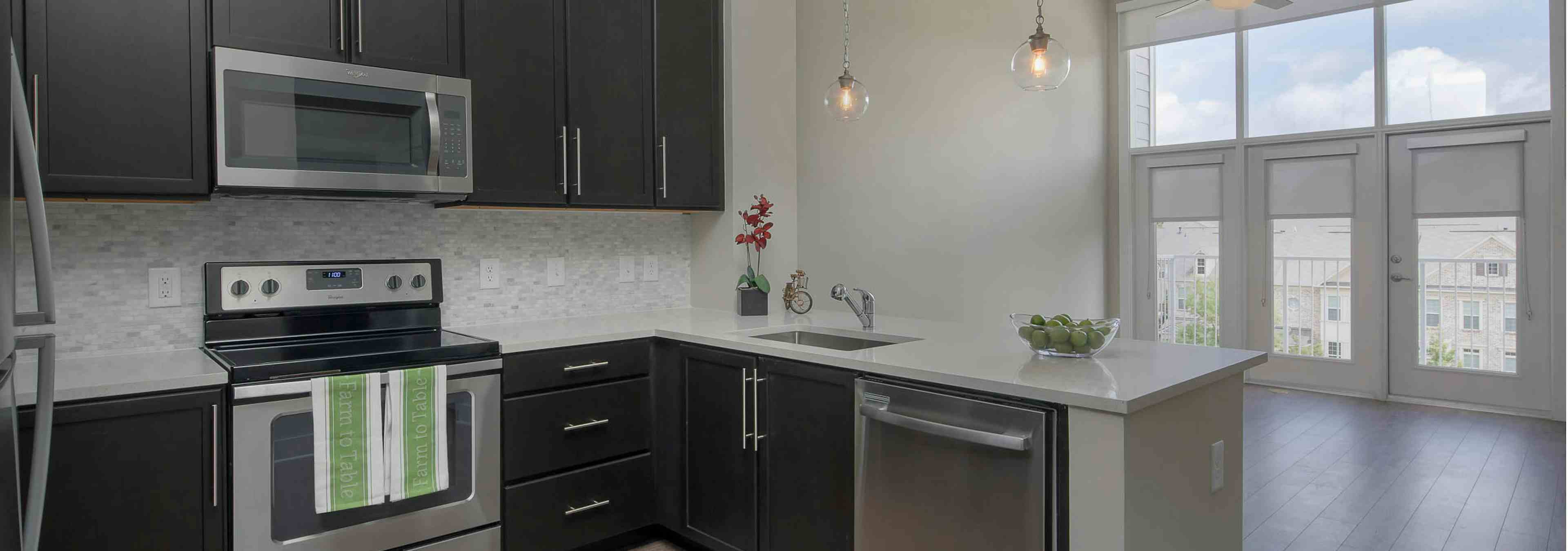 AMLI Buckhead kitchen with black cabinets and white countertops with modern light fixtures and stainless steel appliances