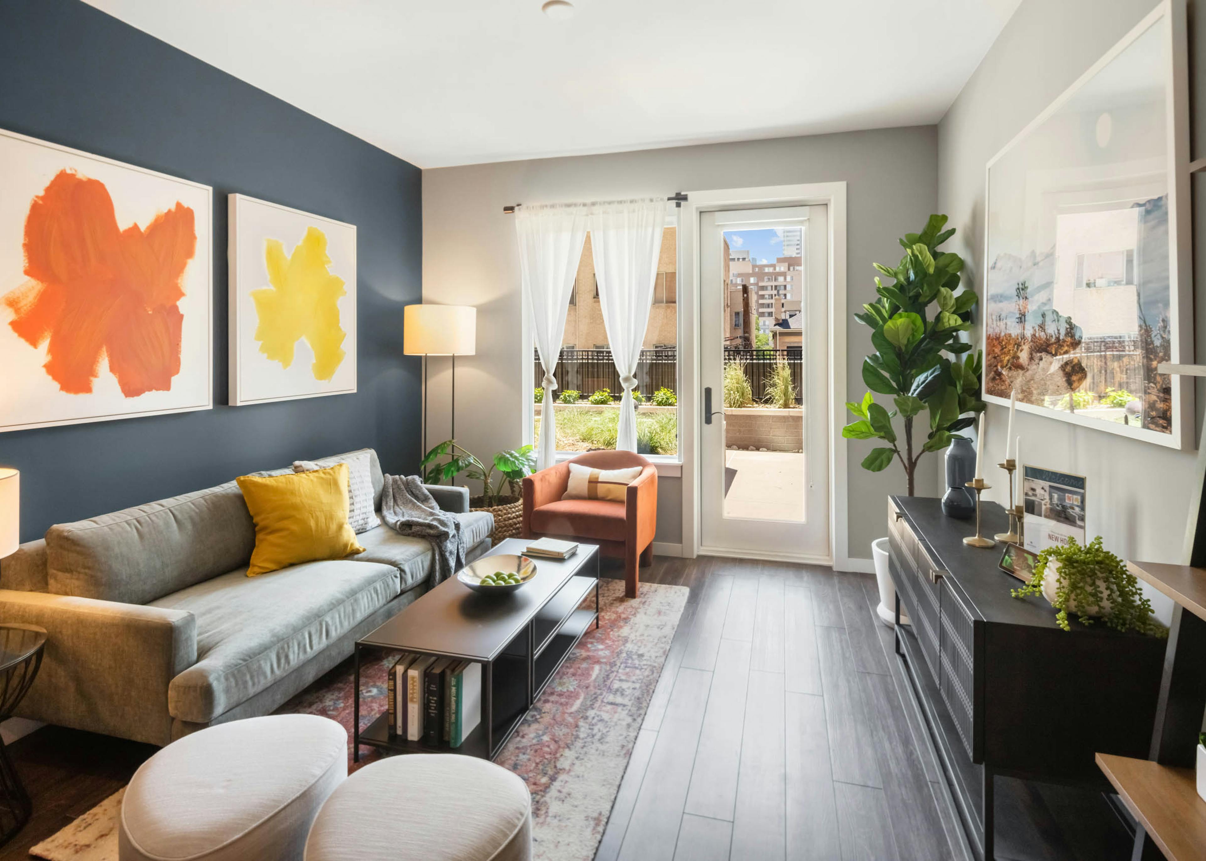Bright AMLI at Uptown apartment living room with orange and yellow artwork on dark blue accent wall and door leading to patio