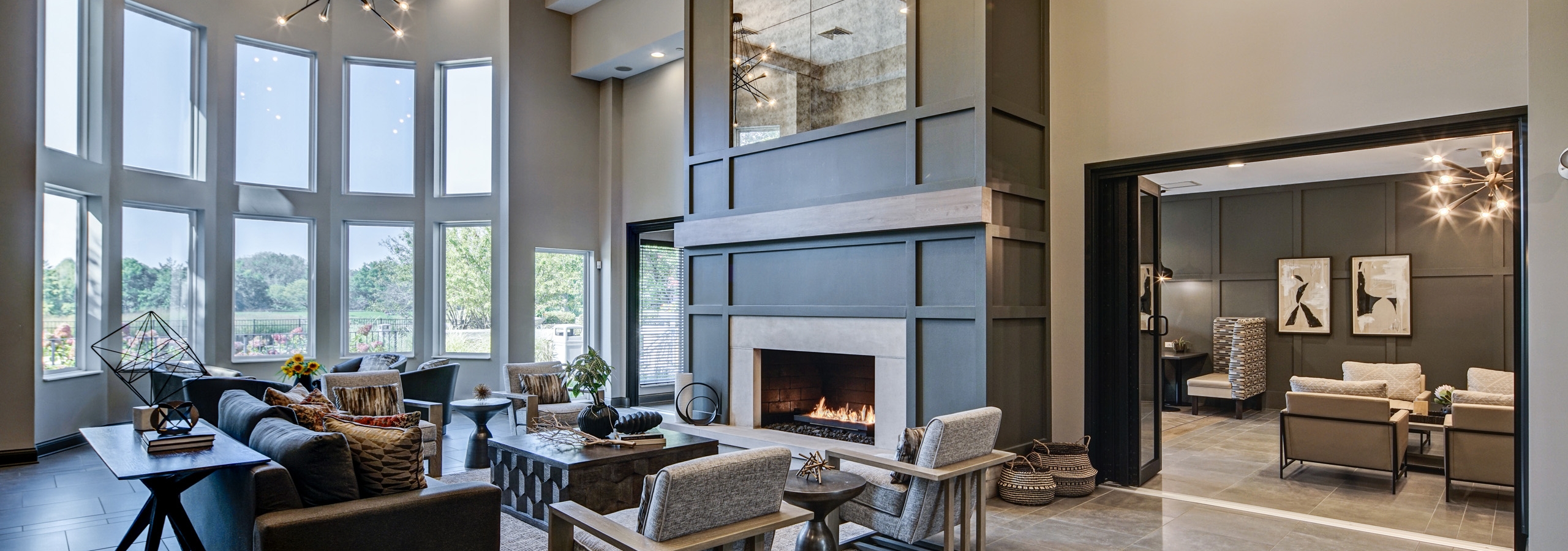 AMLI at Seven Bridges great room with modern gray décor with seating areas and two-story lit fireplace and wall of windows