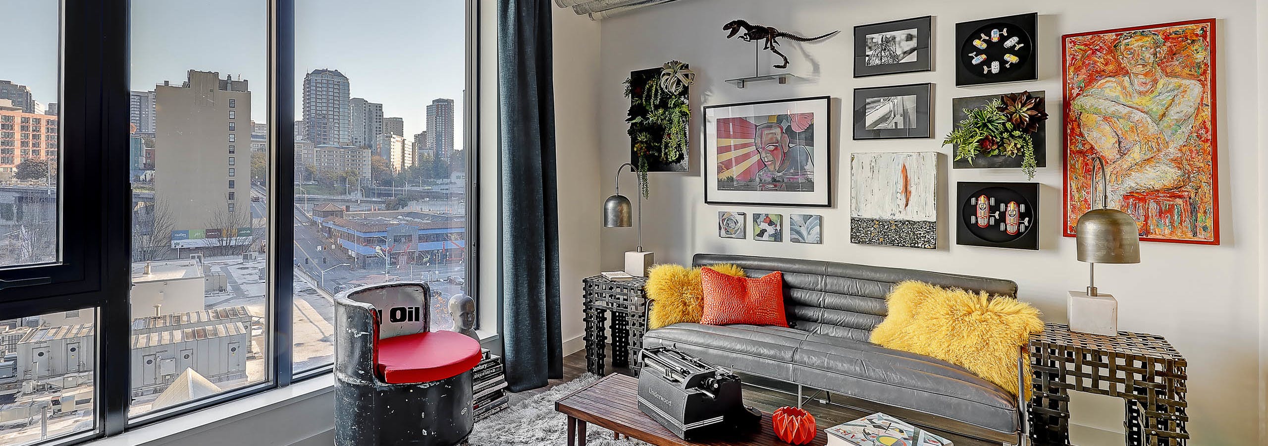 Interior view of apartment of AMLI Arc living room with white walls and large windows with view of downtown Seattle and artwork