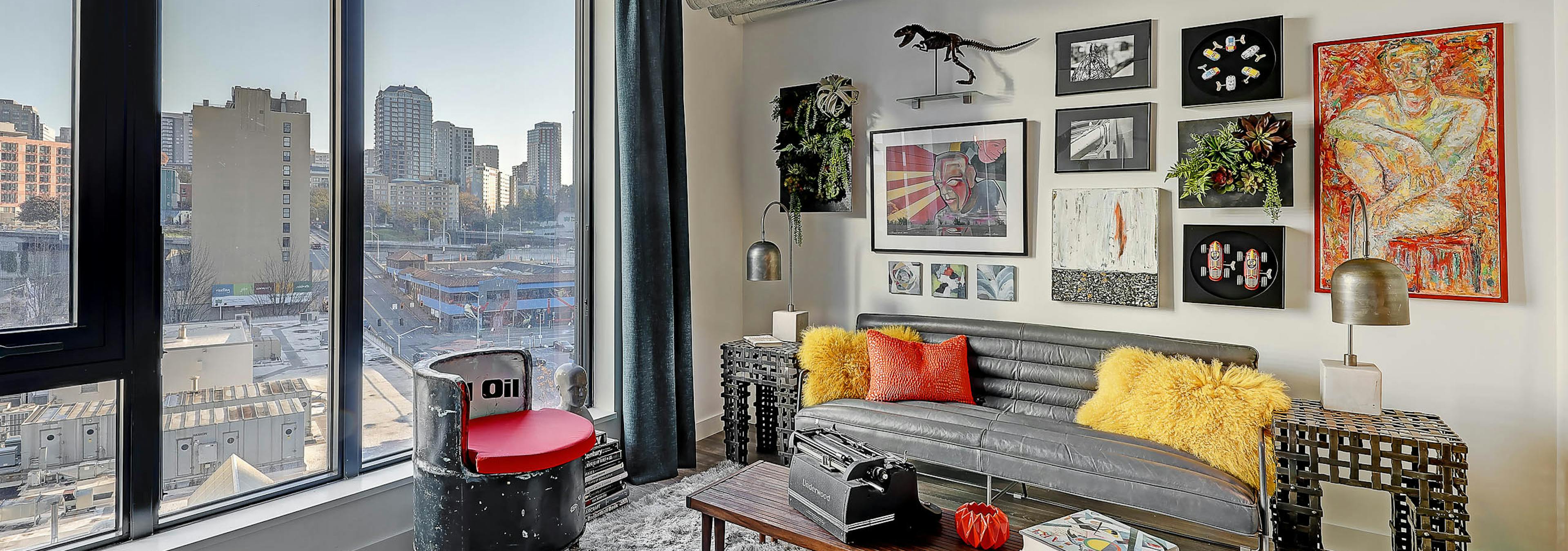 Interior view of apartment of AMLI Arc living room with white walls and large windows with view of downtown Seattle and artwork   