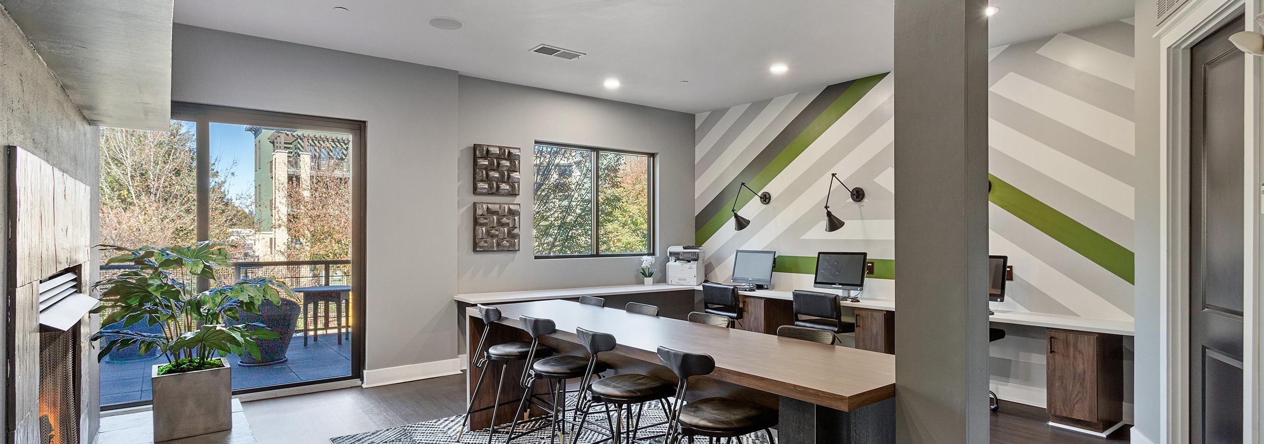 Interior view of AMLI Parkside cyber café with striped accent wall and long desks with computers and chairs and a gray pillar