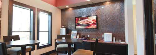 Interior view of java cafe at AMLI at Escena apartments with coffee serving bar and tables and chairs and big screen TV