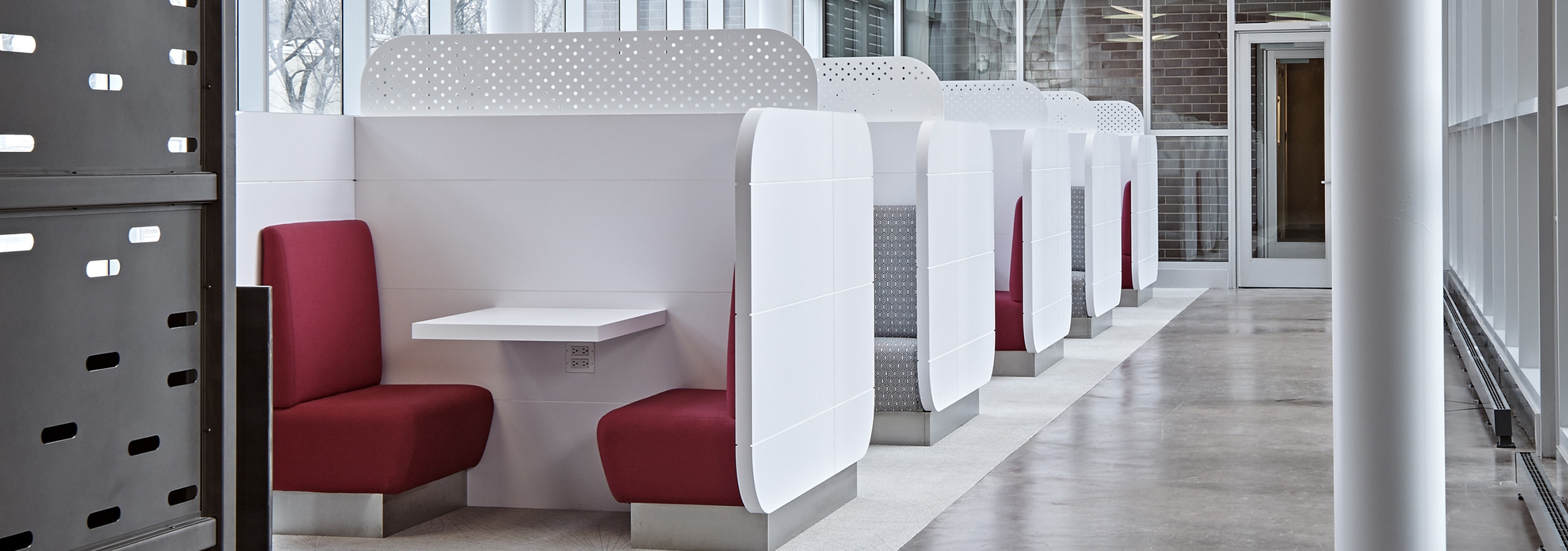 Interior view of the cyber lounge at AMLI Lofts apartment community that has crisp white booths paired with bright red seats