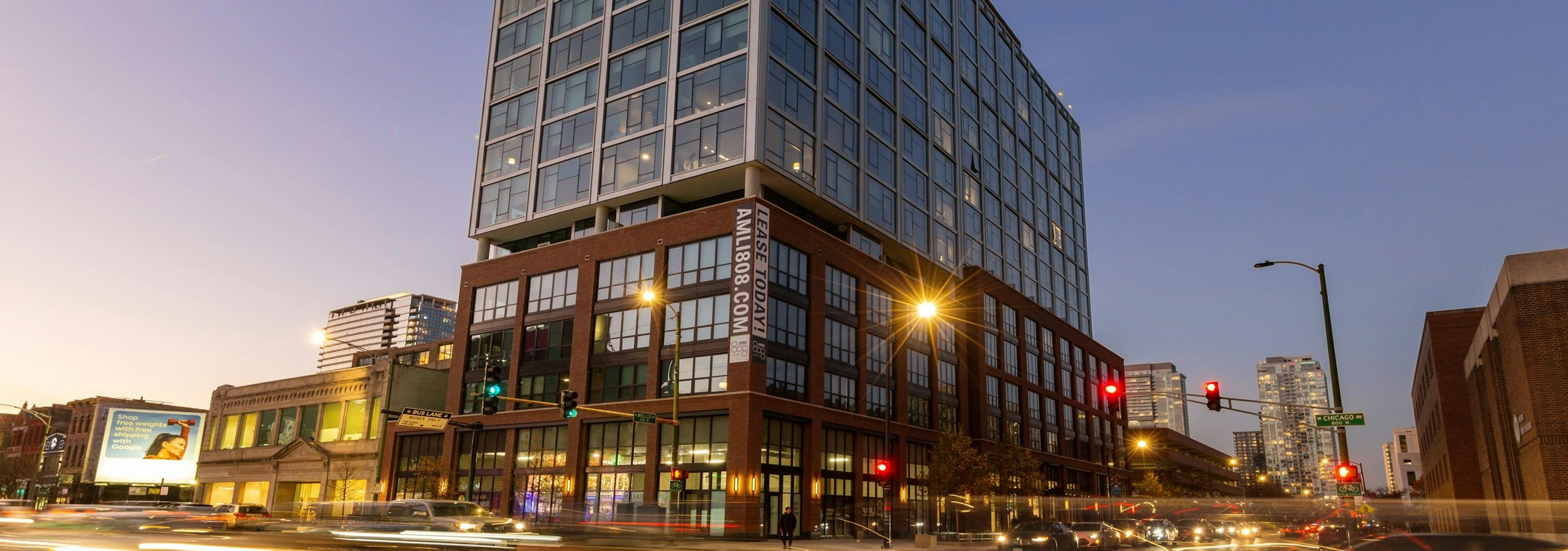 Modern AMLI 808 building exterior at nighttime with blurred cars and lights on the surrounding Chicago streets 