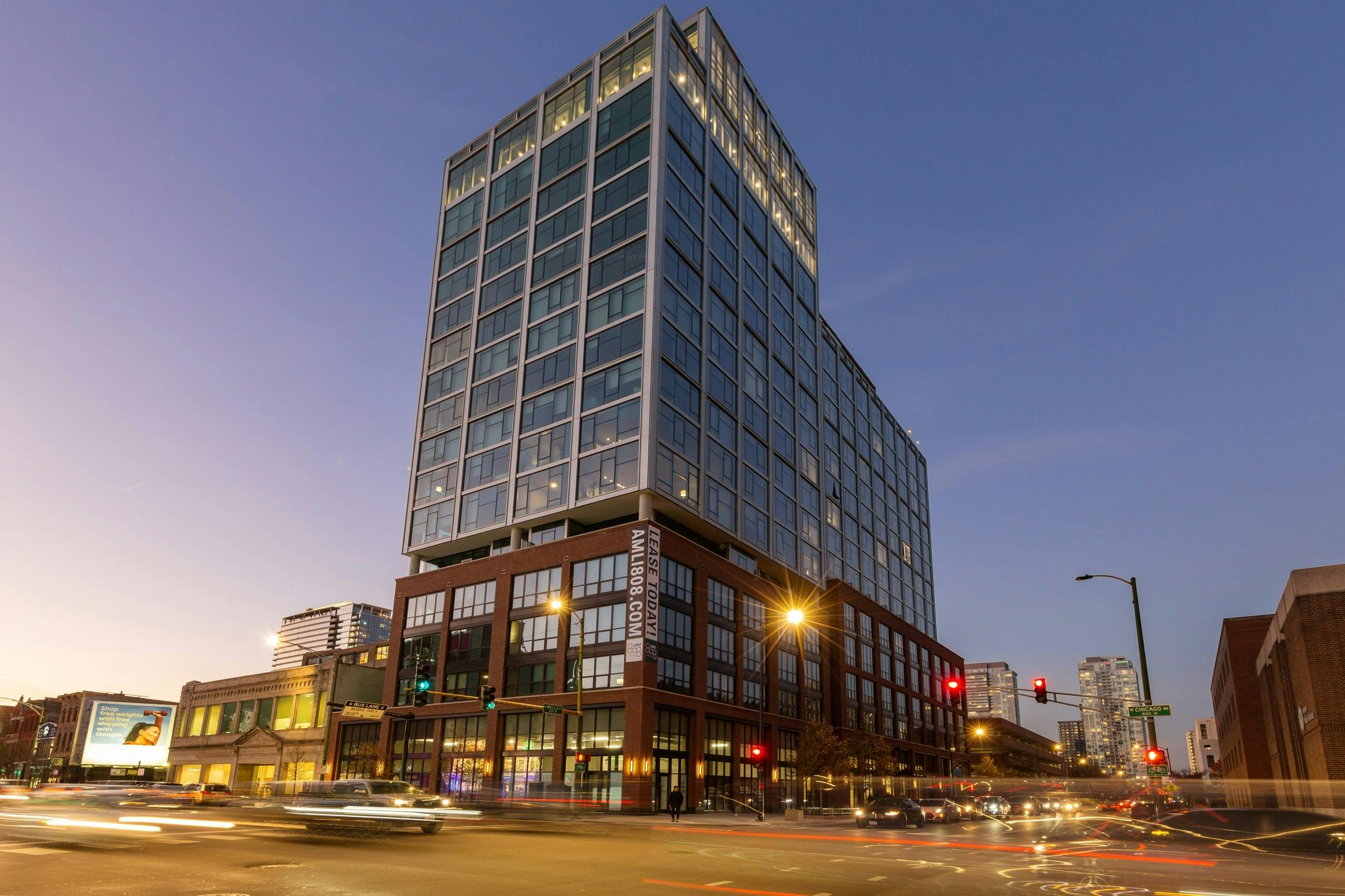 Modern AMLI 808 building exterior at nighttime with blurred cars and lights on the surrounding Chicago streets 