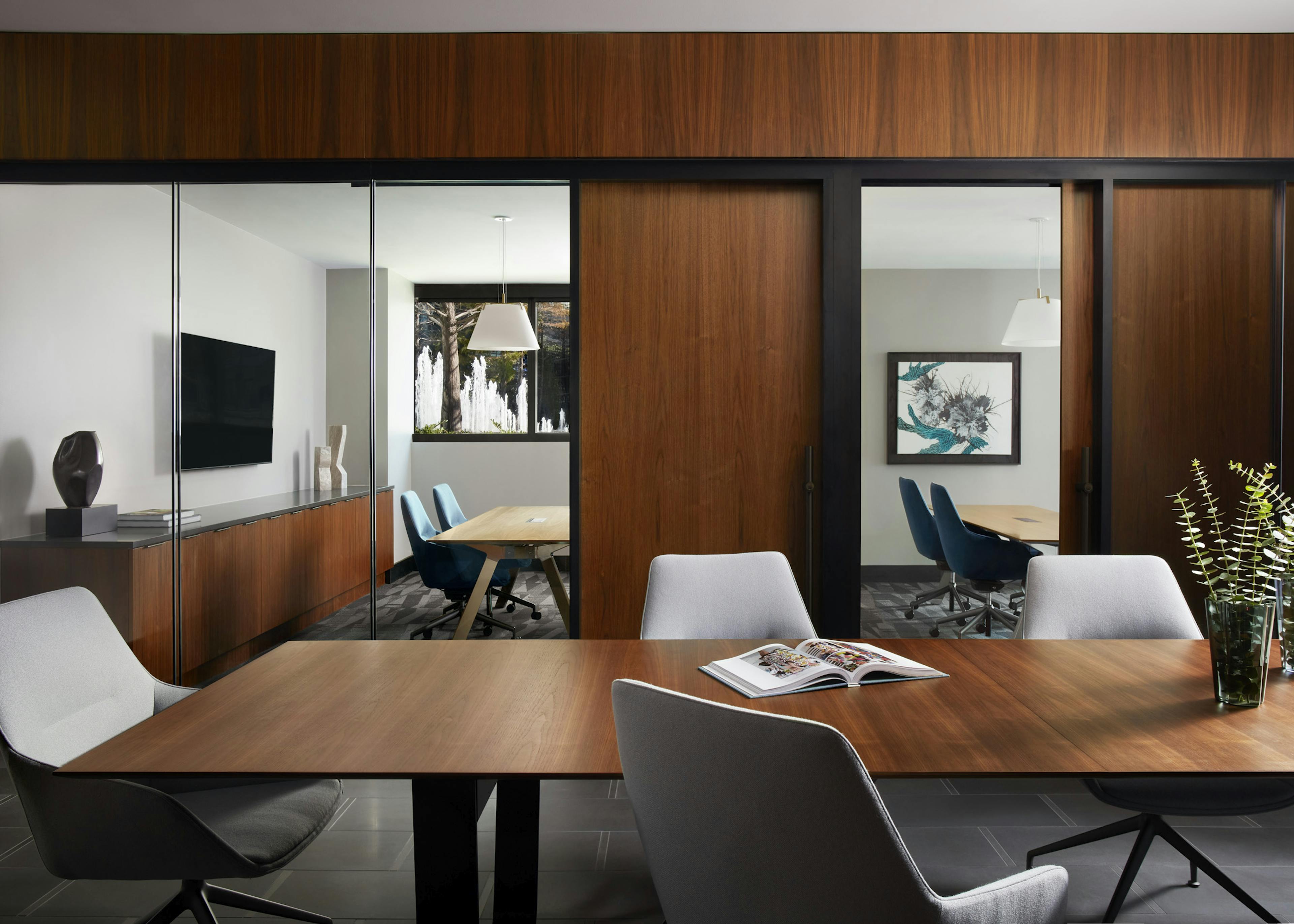 Conference room at AMLI Fountain Place apartments with wood table and chairs and sliding doors with view of private offices 