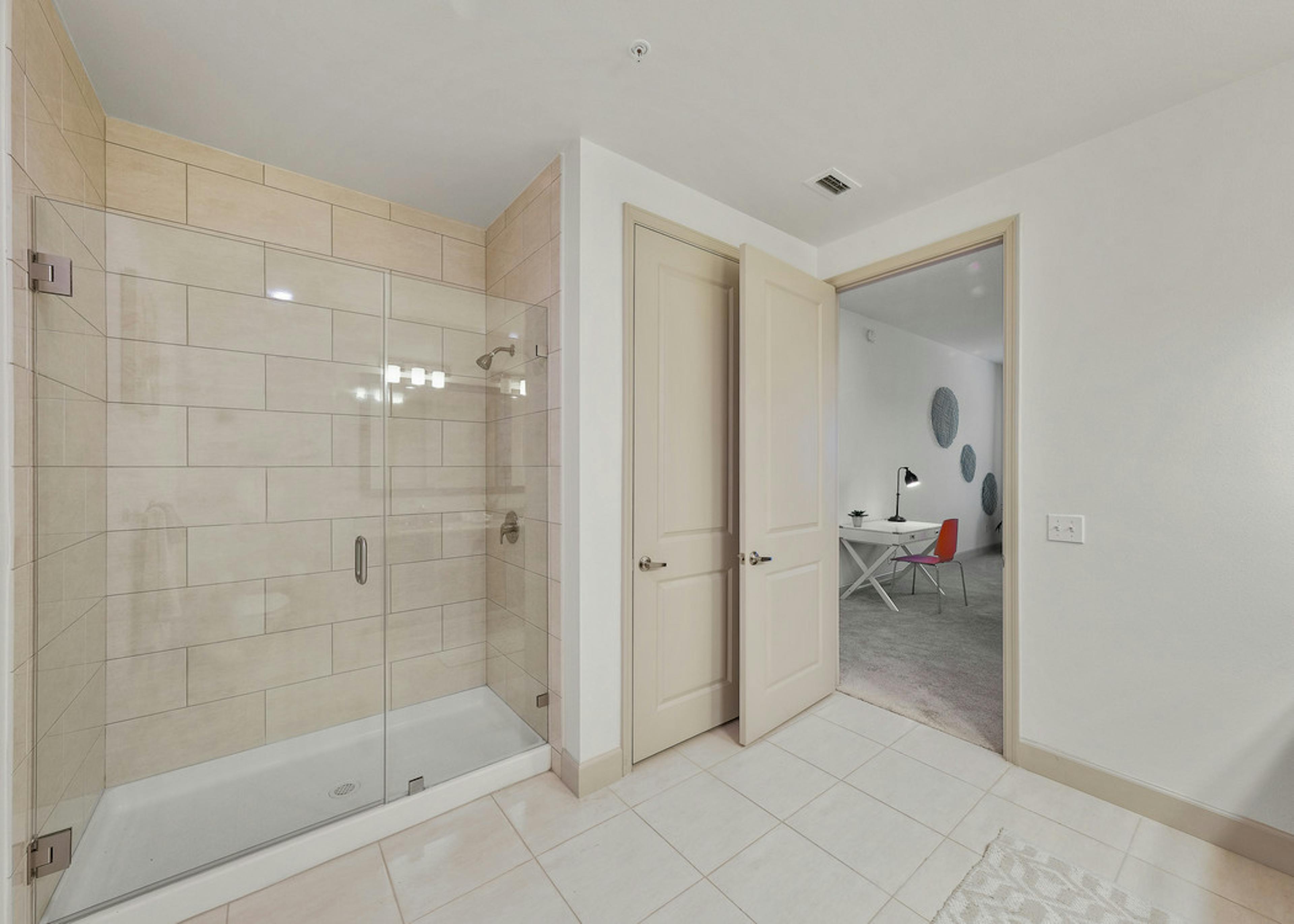  Interior view of AMLI 8800 apartment bathroom with large seamless glass shower enclosure and white ceramic tile floor