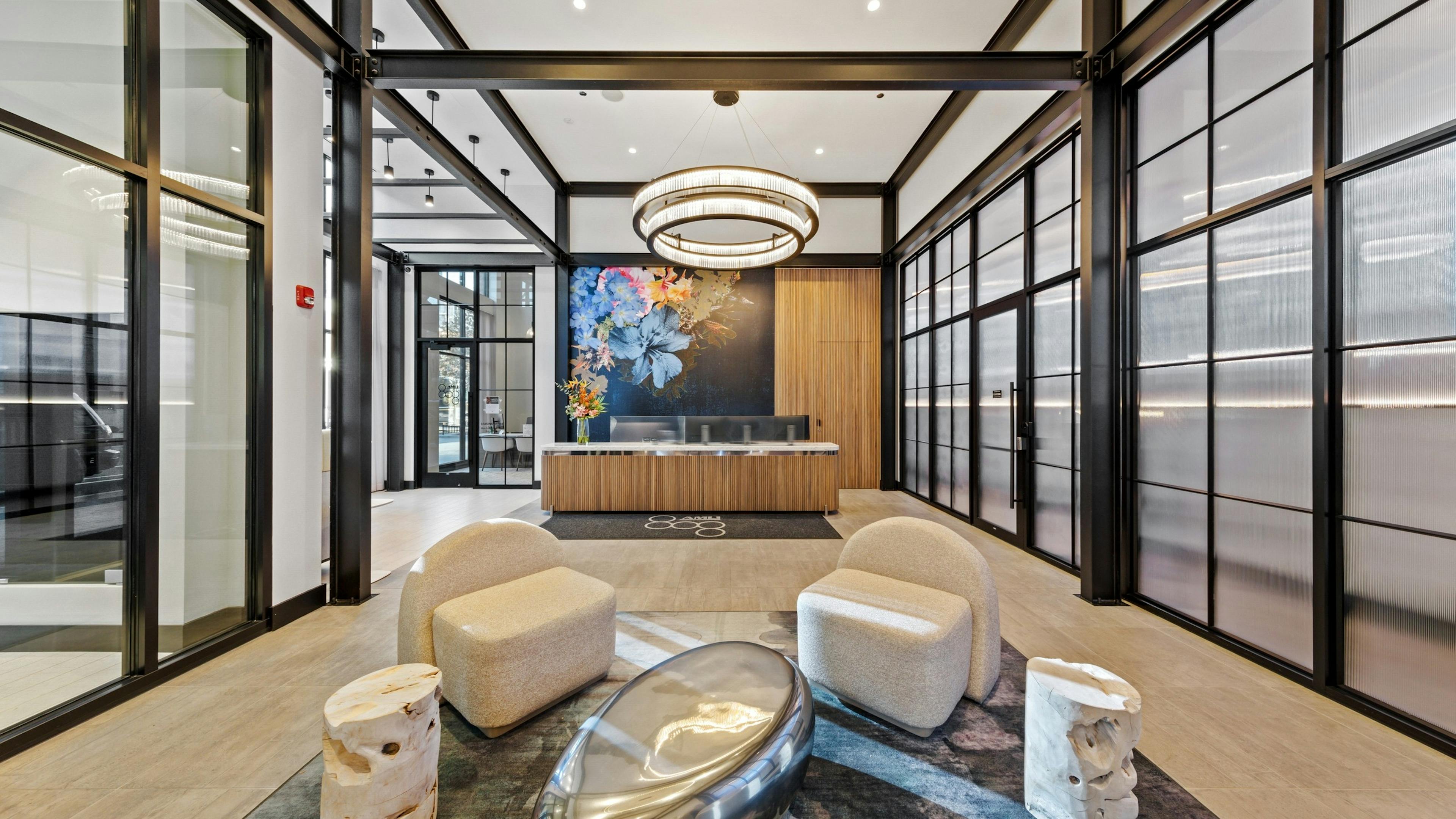AMLI 808 lobby with beige chairs surrounding bold side tables on a modern grey rug with view of reception desk in background