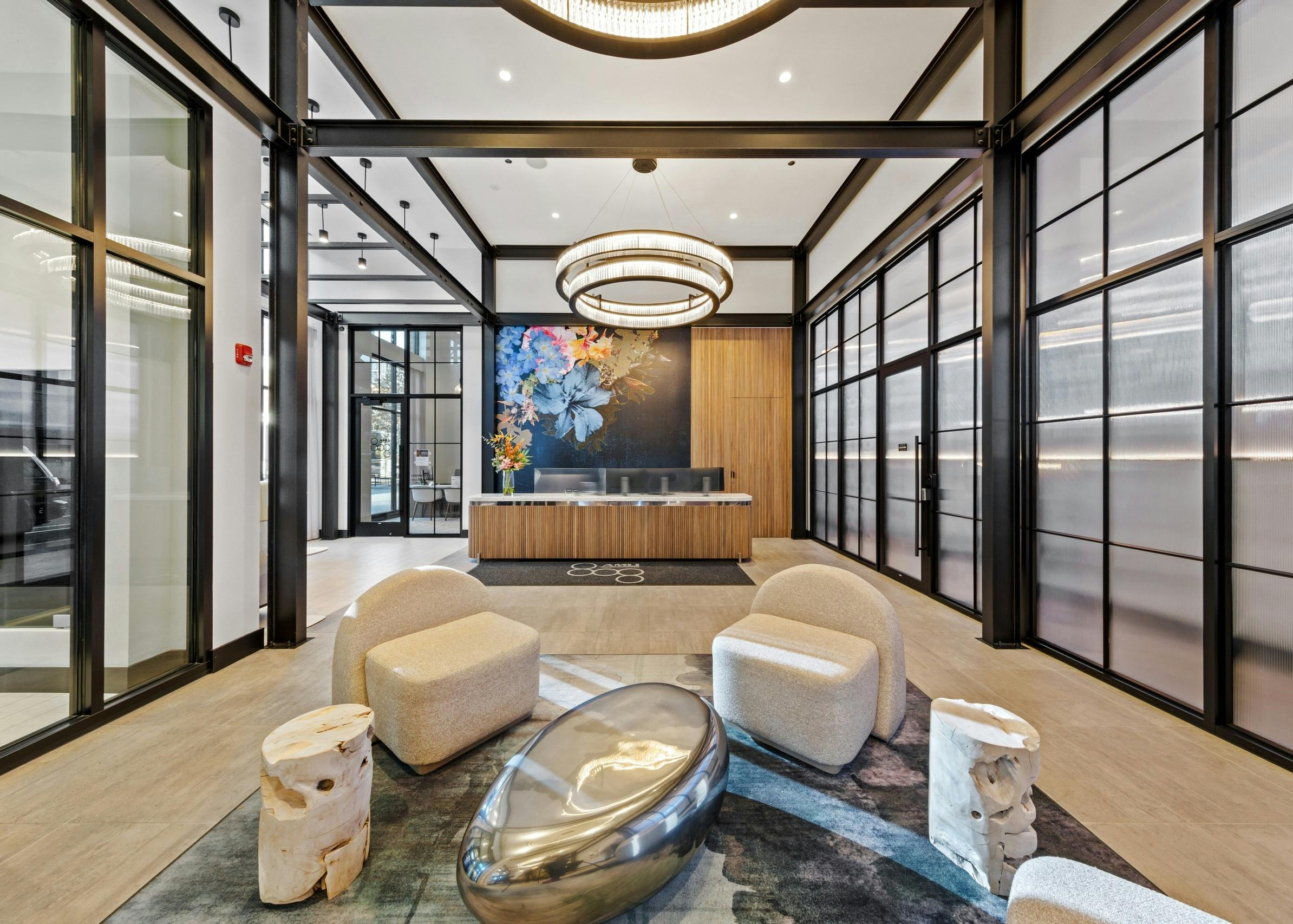 AMLI 808 lobby with beige chairs surrounding bold side tables on a modern grey rug with view of reception desk in background