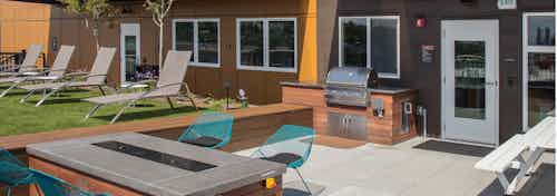 One of three rooftop decks at AMLI Wallingford with BBQ fire pit lounge seating and turf grass for lawn games