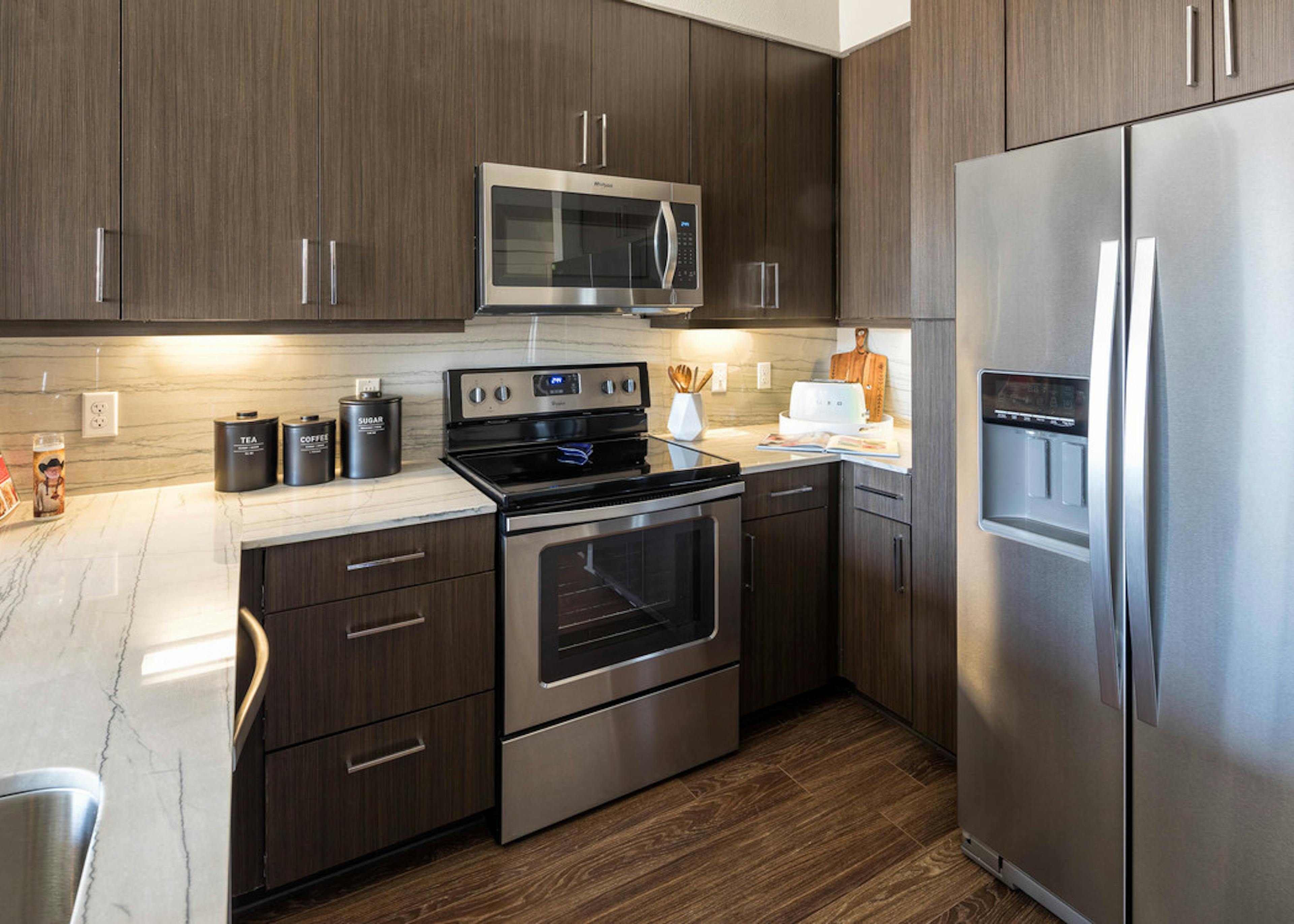 Close up view of AMLI on Aldrich apartment kitchen with dark cabinets and a beige backsplash with white countertops