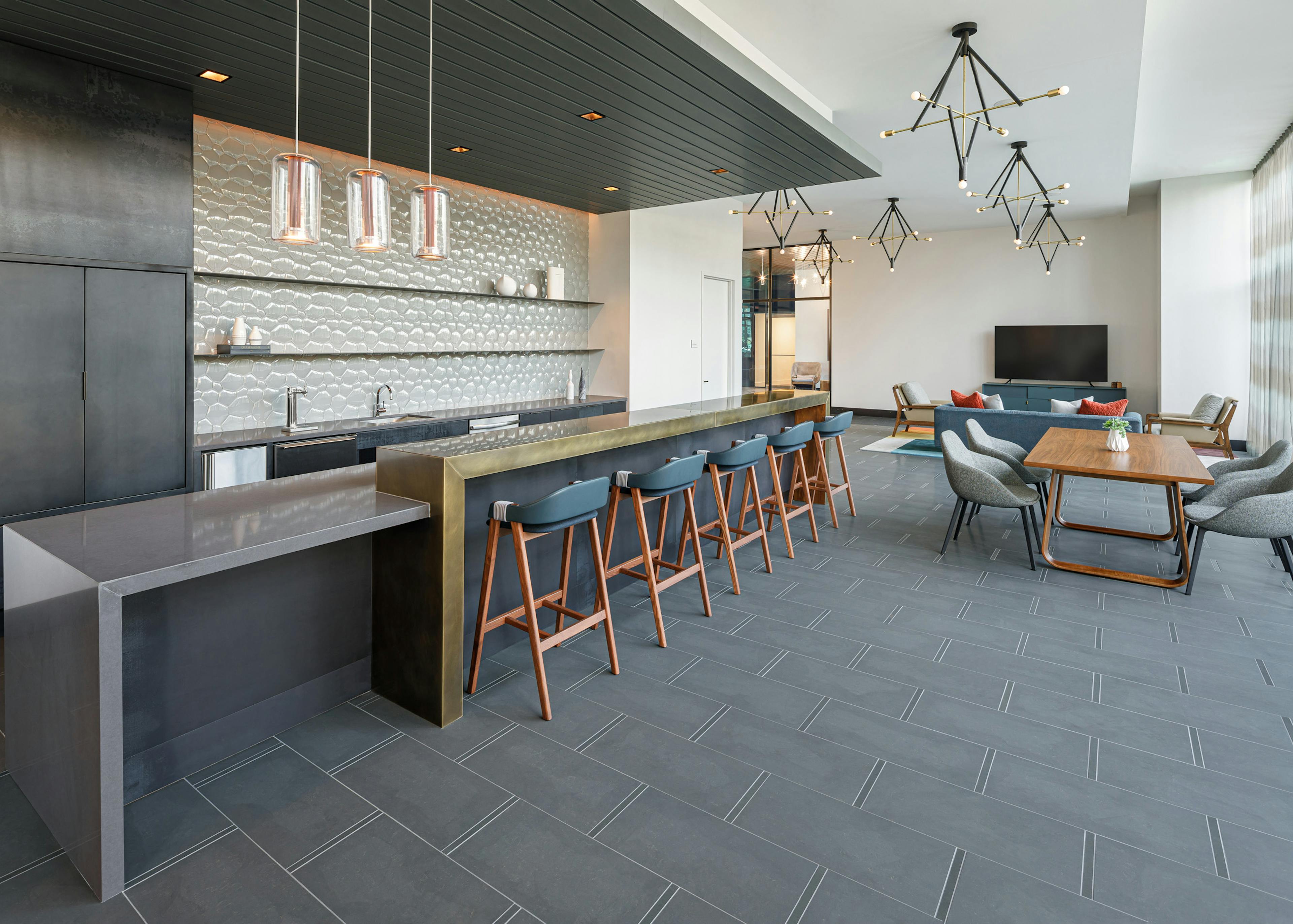 Resident lounge and AMLI Fountain Place apartments with serving kitchen and bronze counter with stools and other seating nearby