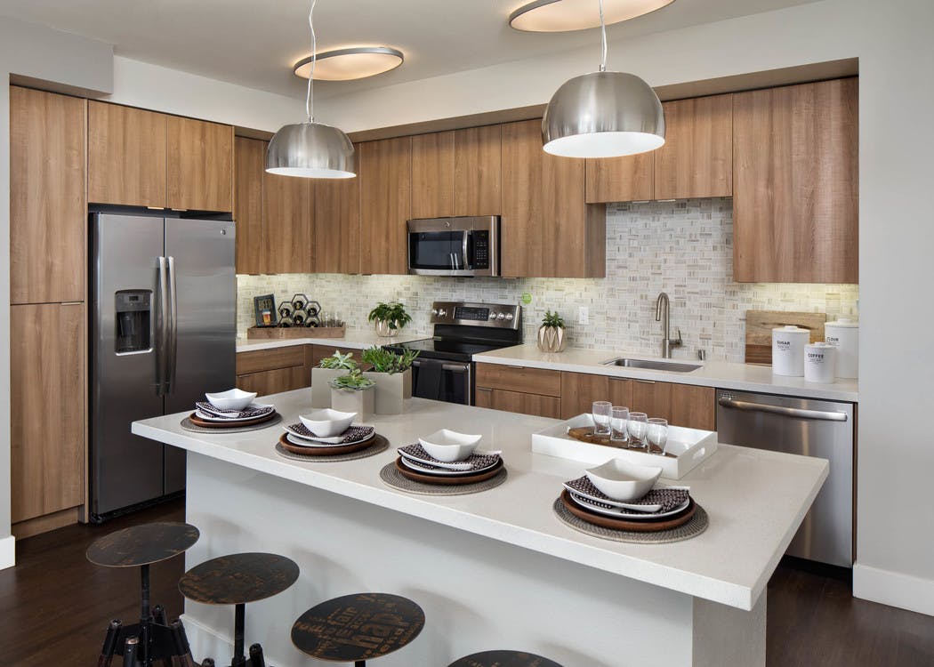 AMLI Uptown Orange apartment kitchen with light wood cabinets and designer tile backsplash and stainless steel appliances