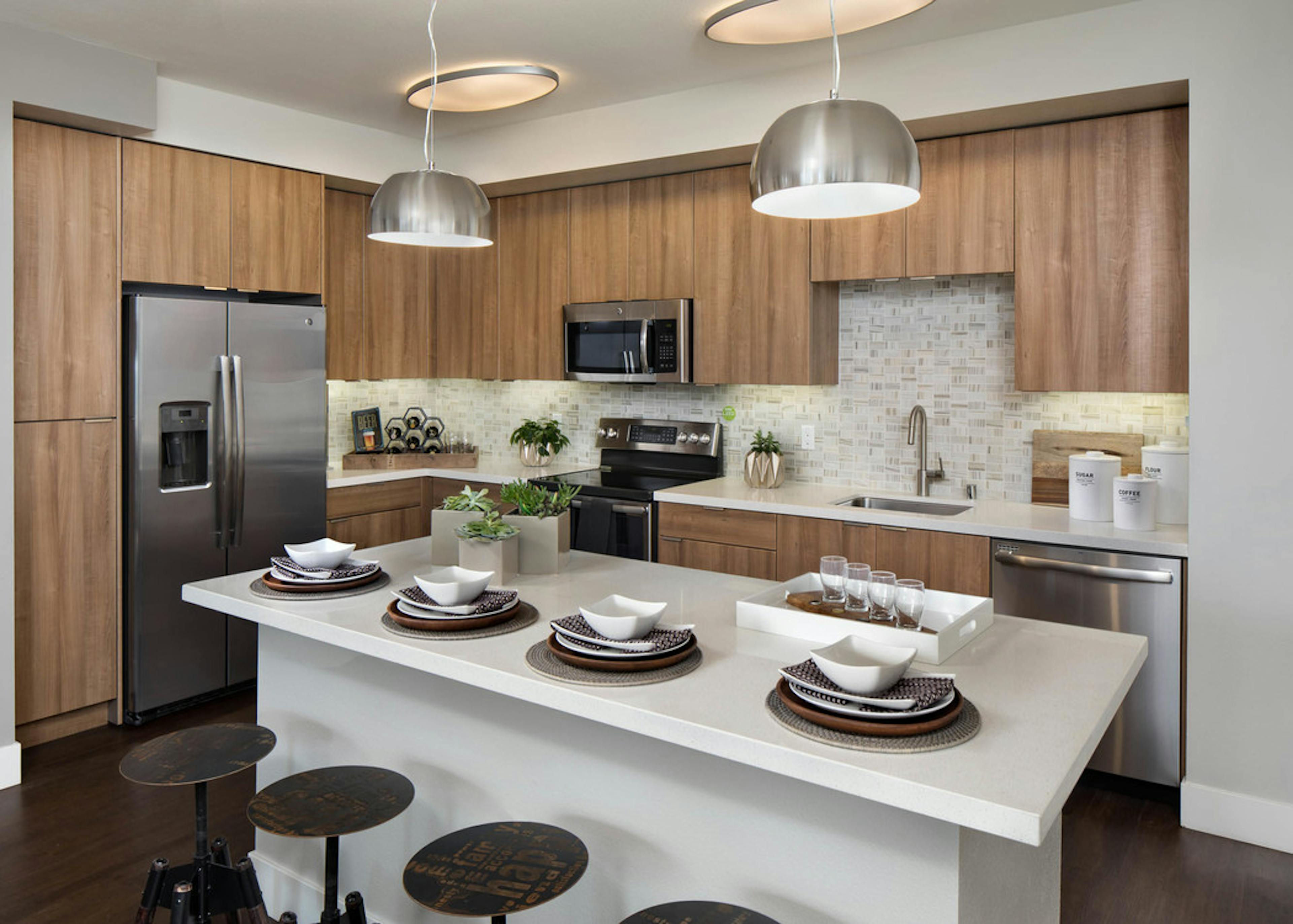 AMLI Uptown Orange apartment kitchen with light wood cabinets and designer tile backsplash and stainless steel appliances