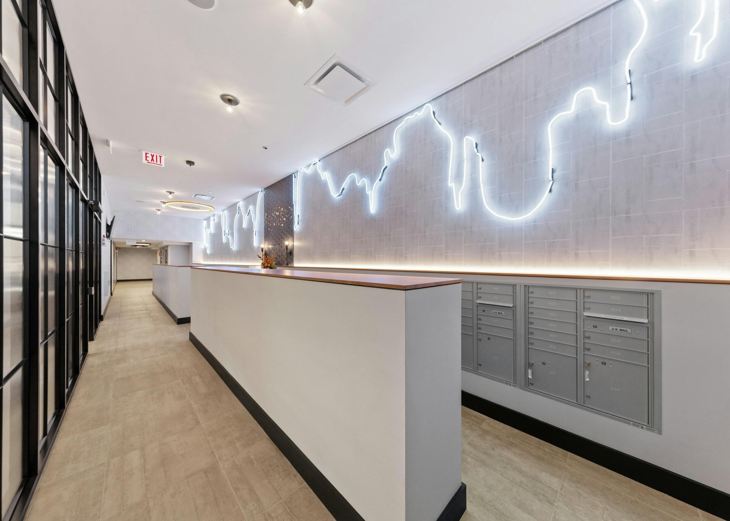 AMLI 808 mailroom featuring grey mail boxes and beige flooring with unique lights lining the full length of light grey walls