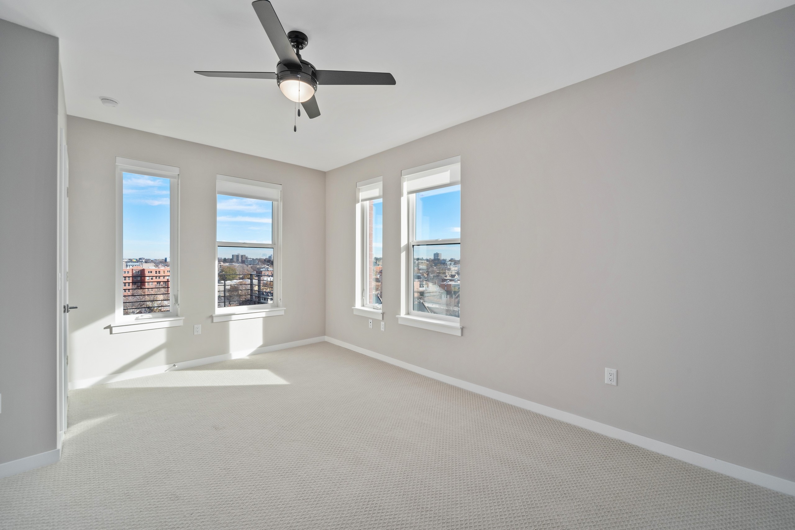 Empty AMLI at Uptown apartment bedroom with neutral carpet  and light grey walls with four windows letting in natural light