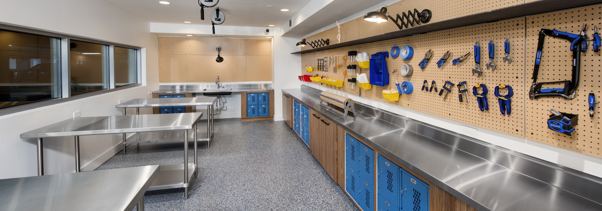 DIY maker space at AMLI Decatur with tools on peg wall and lockers with a sink as well as work areas for residents to create
