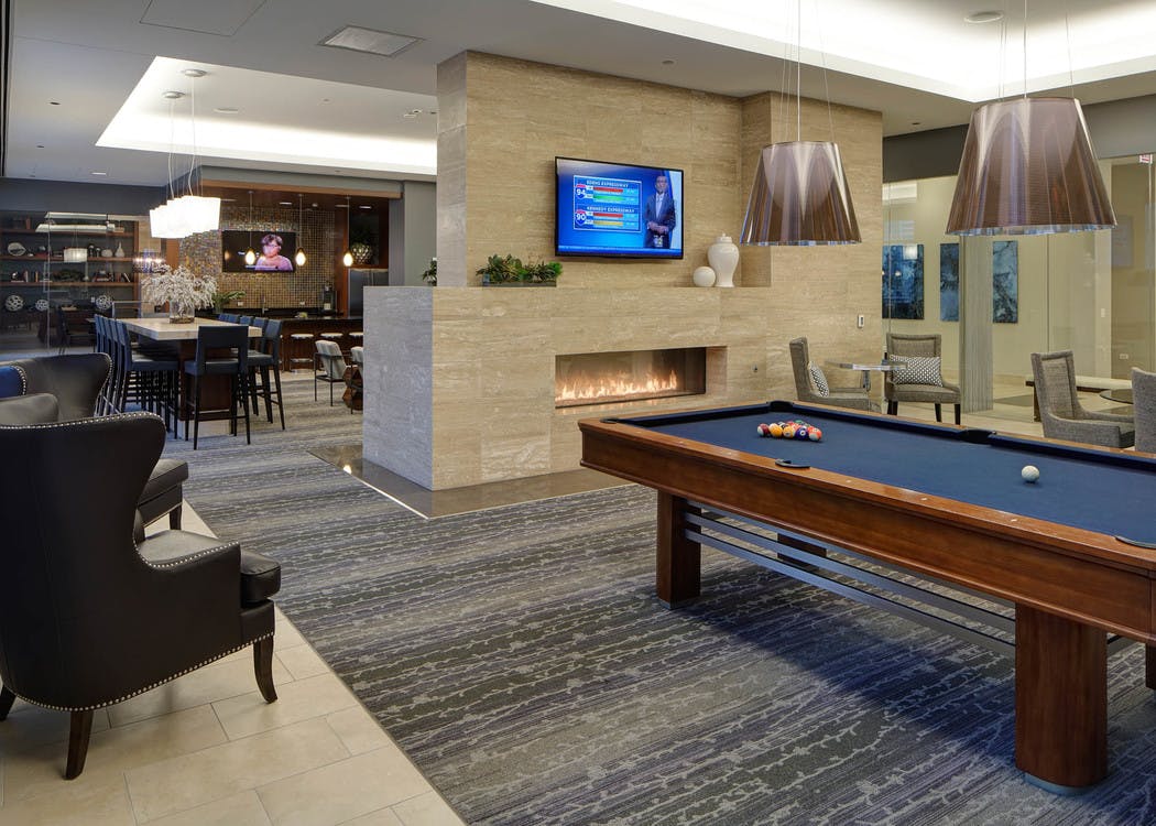 Clubroom at AMLI River North with billiards and a large fireplace as well as a flat screen TV and multiple seating options