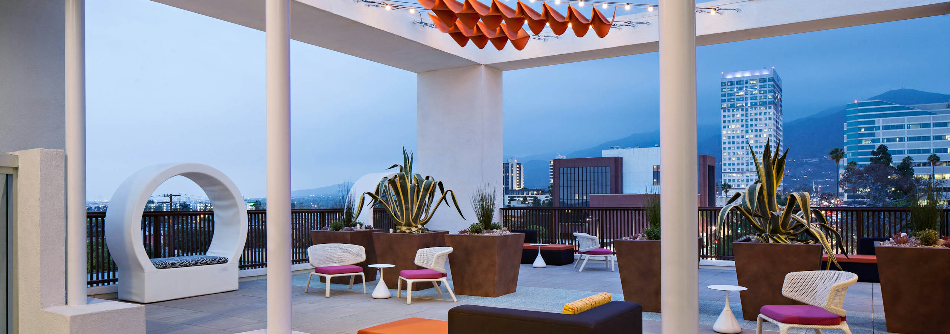 Exterior view of Sky deck overlooking the city lights at dusk with various lounge seating at AMLI Lex on Orange apartments