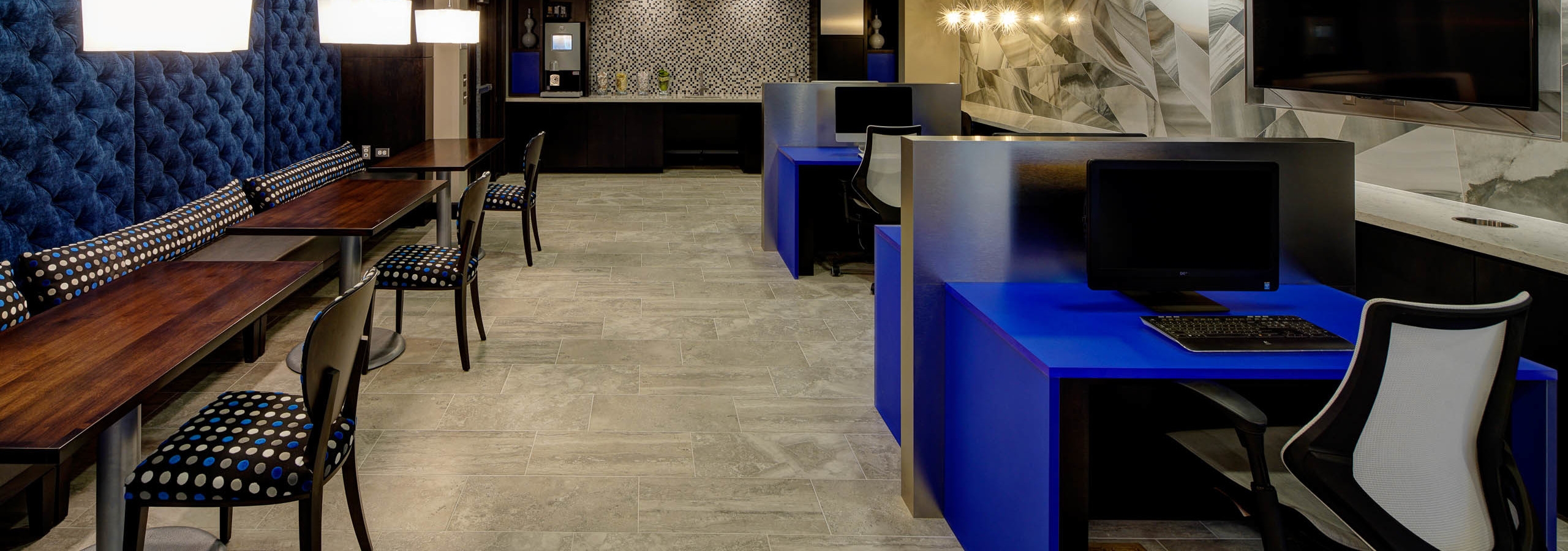 Interior of business center at AMLI Deerfield equipped with computers on blue desks and a co working space and coffee machine