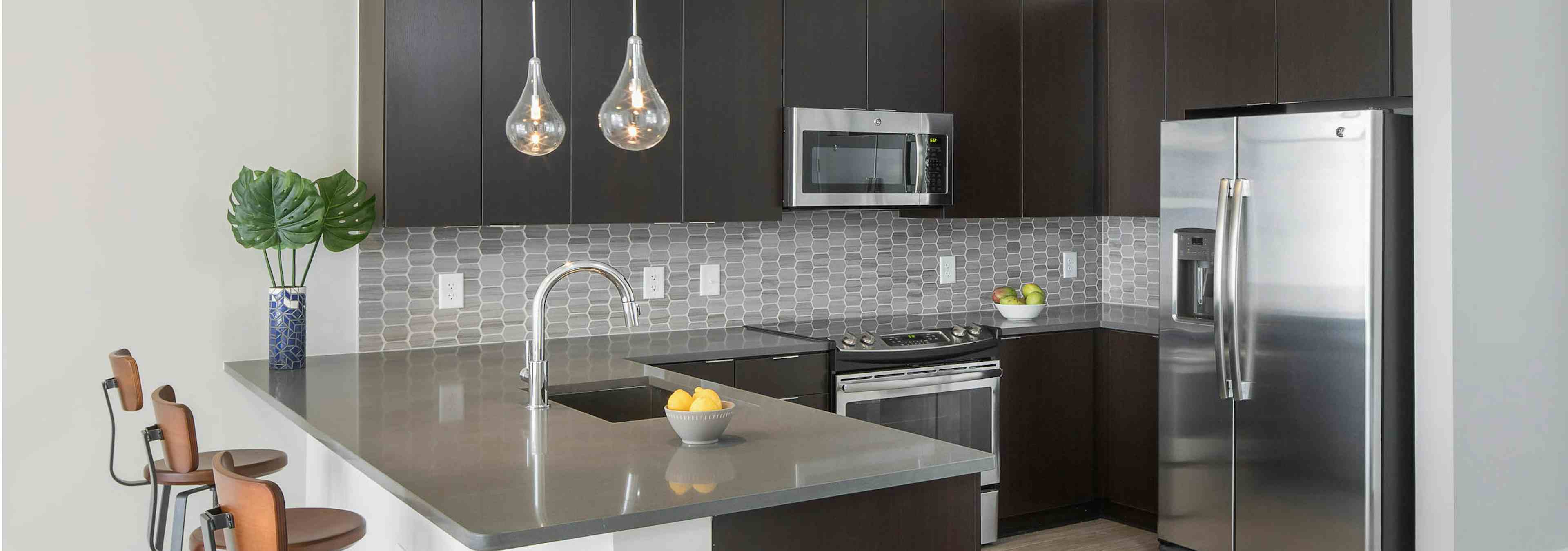 Interior of AMLI Arts Center Kitchen with black cabinets and stainless steel appliances with a grey patterned backsplash