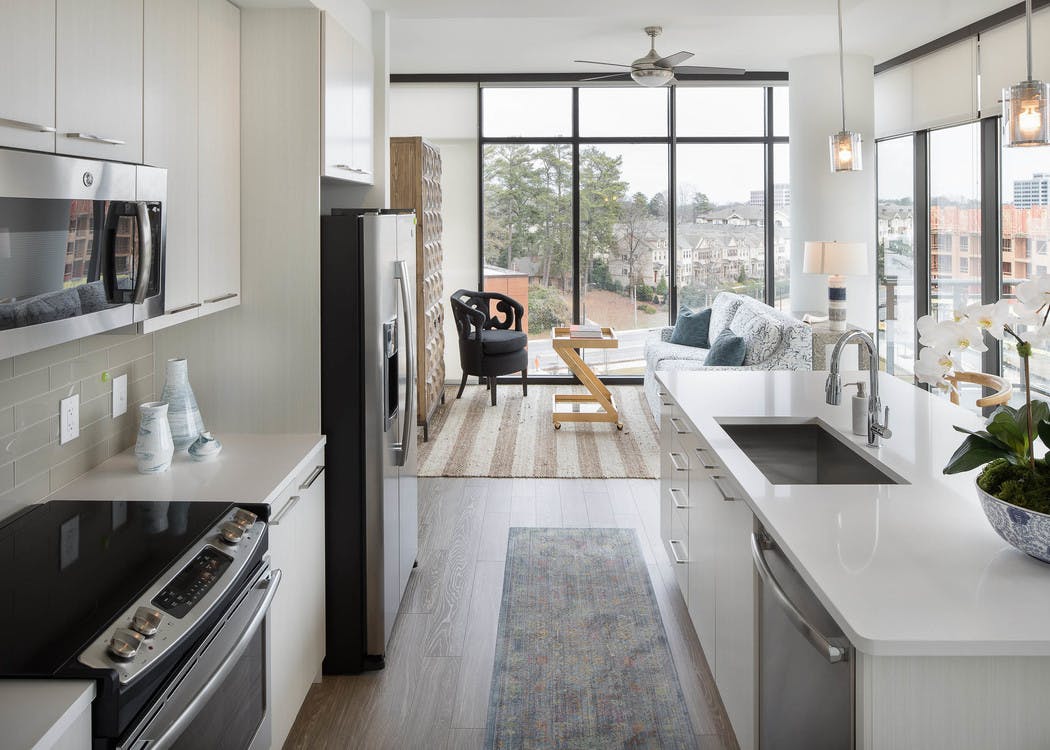 AMLI 3464 kitchen with white cabinets and countertops paired with beige backsplash and surrounding floor to ceiling windows