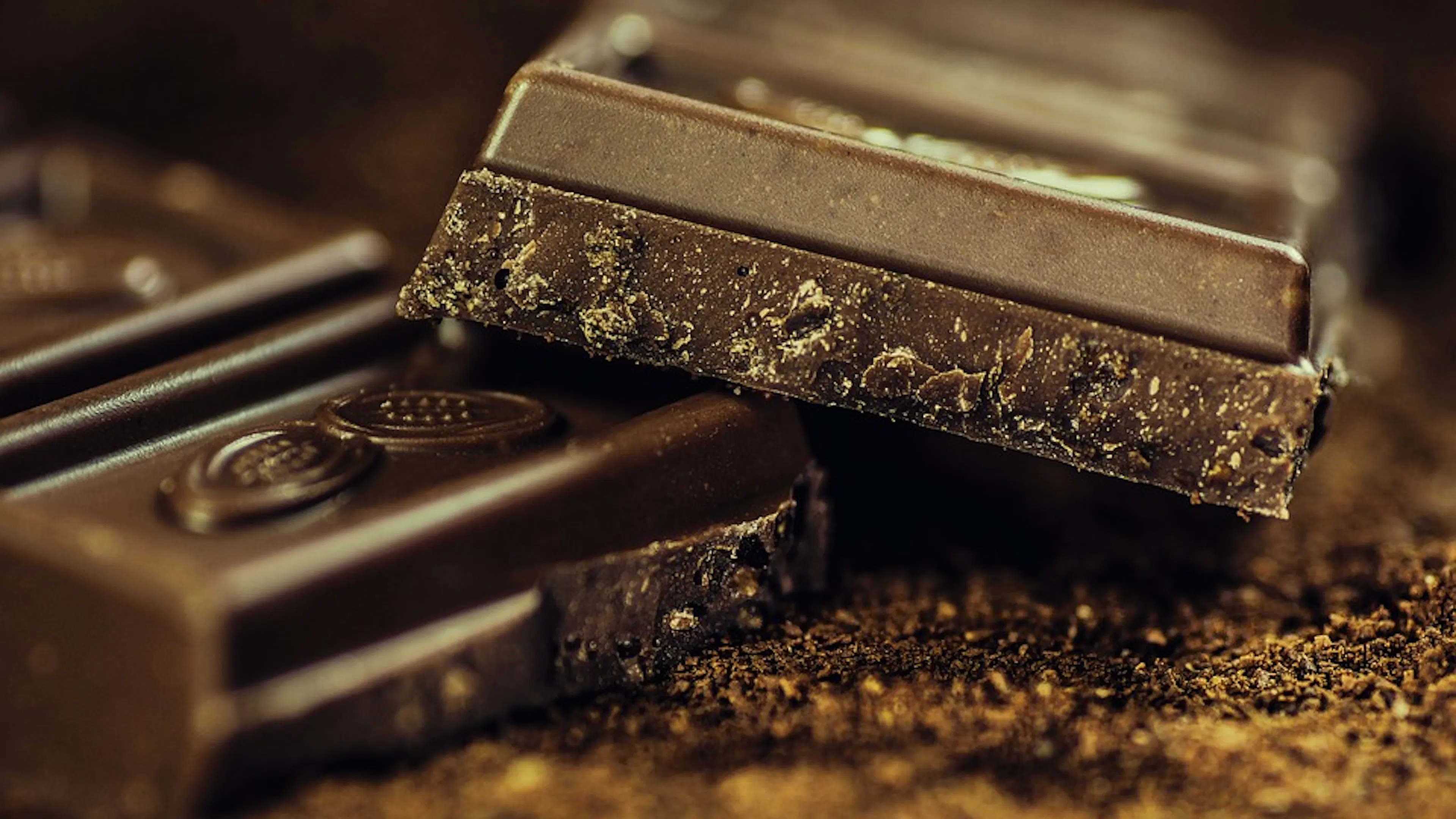 An up close shot of a bar of dark chocolate in low lighting