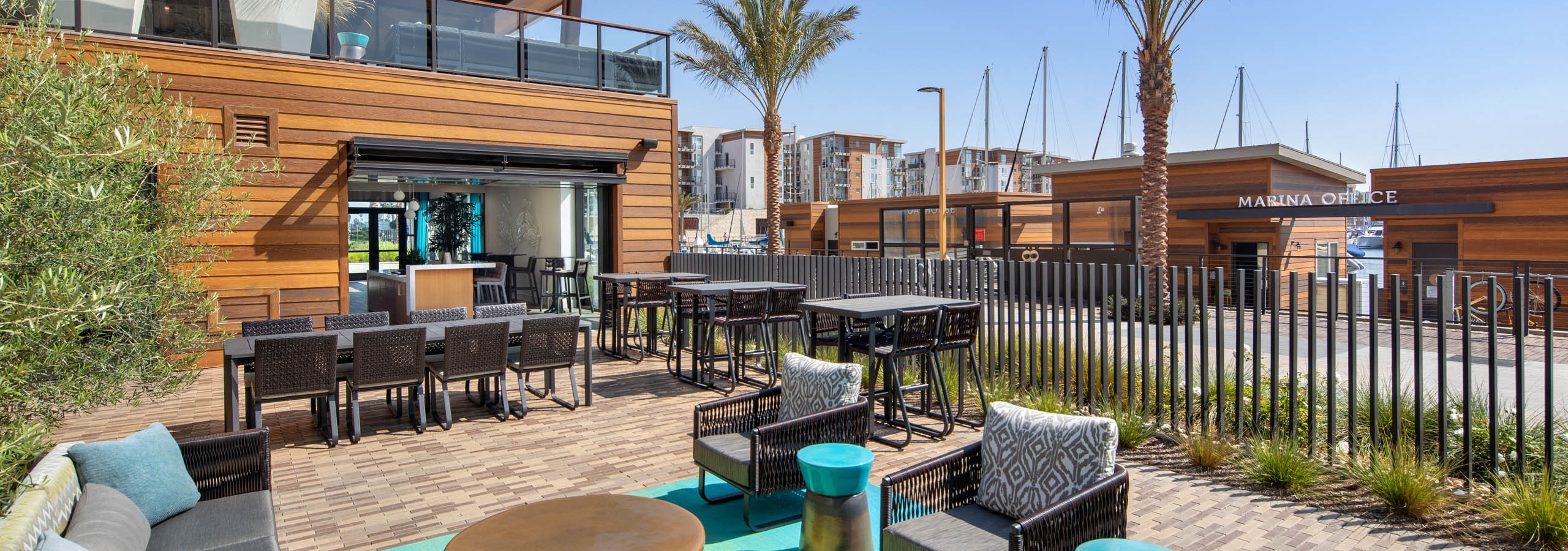 Outdoor lounge area facing the marina office at AMLI Marina Del Rey apartments with various tables and seating options
