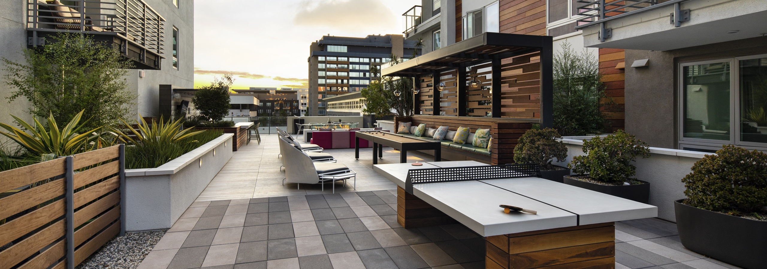 Outdoor gaming courtyard at duck with wood paneling on side of building and ping pong table and seating at AMLI Park Broadway