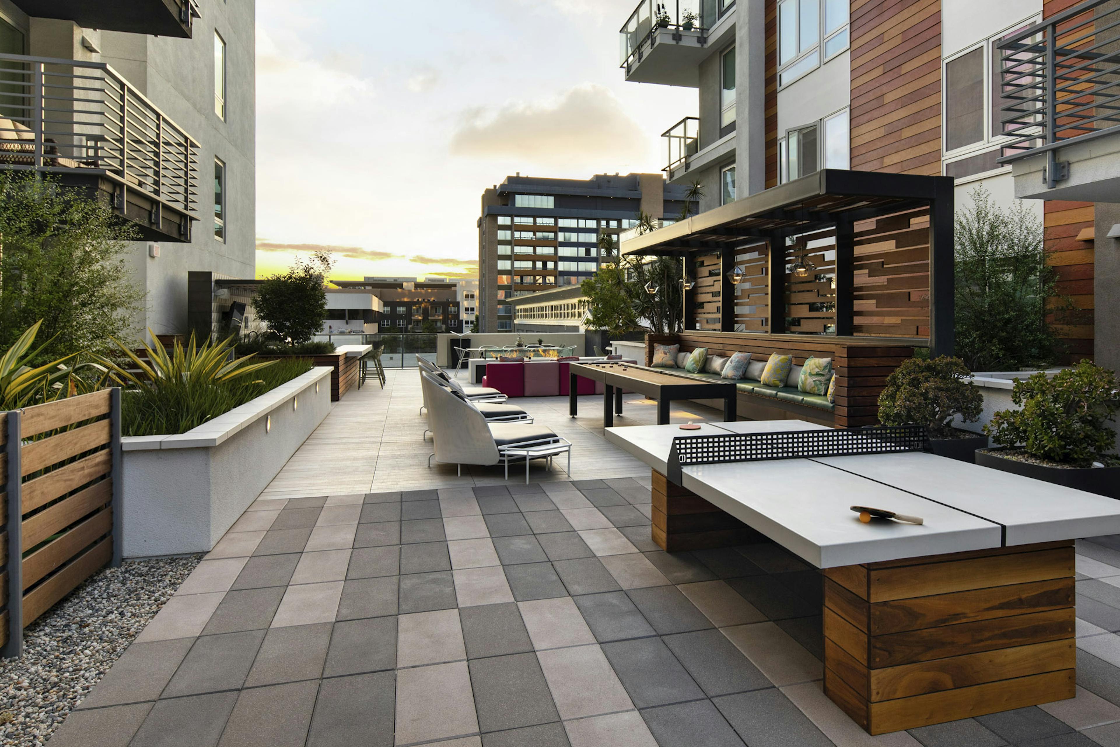 Outdoor gaming courtyard at duck with wood paneling on side of building and ping pong table and seating at AMLI Park Broadway