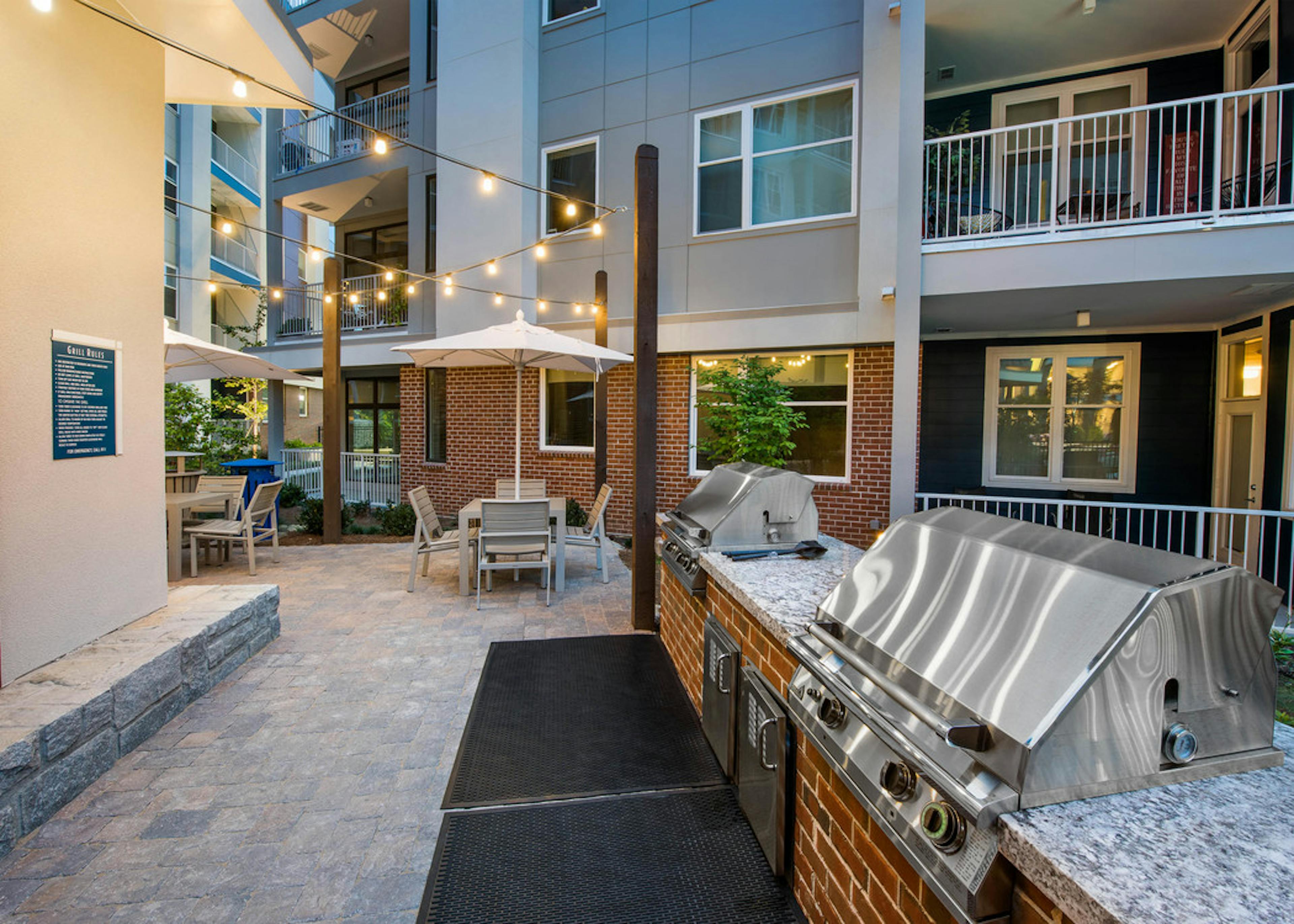 AMLI Buckhead barbecue area with grills and outdoor counter space and stone flooring leading to area with tables and chairs