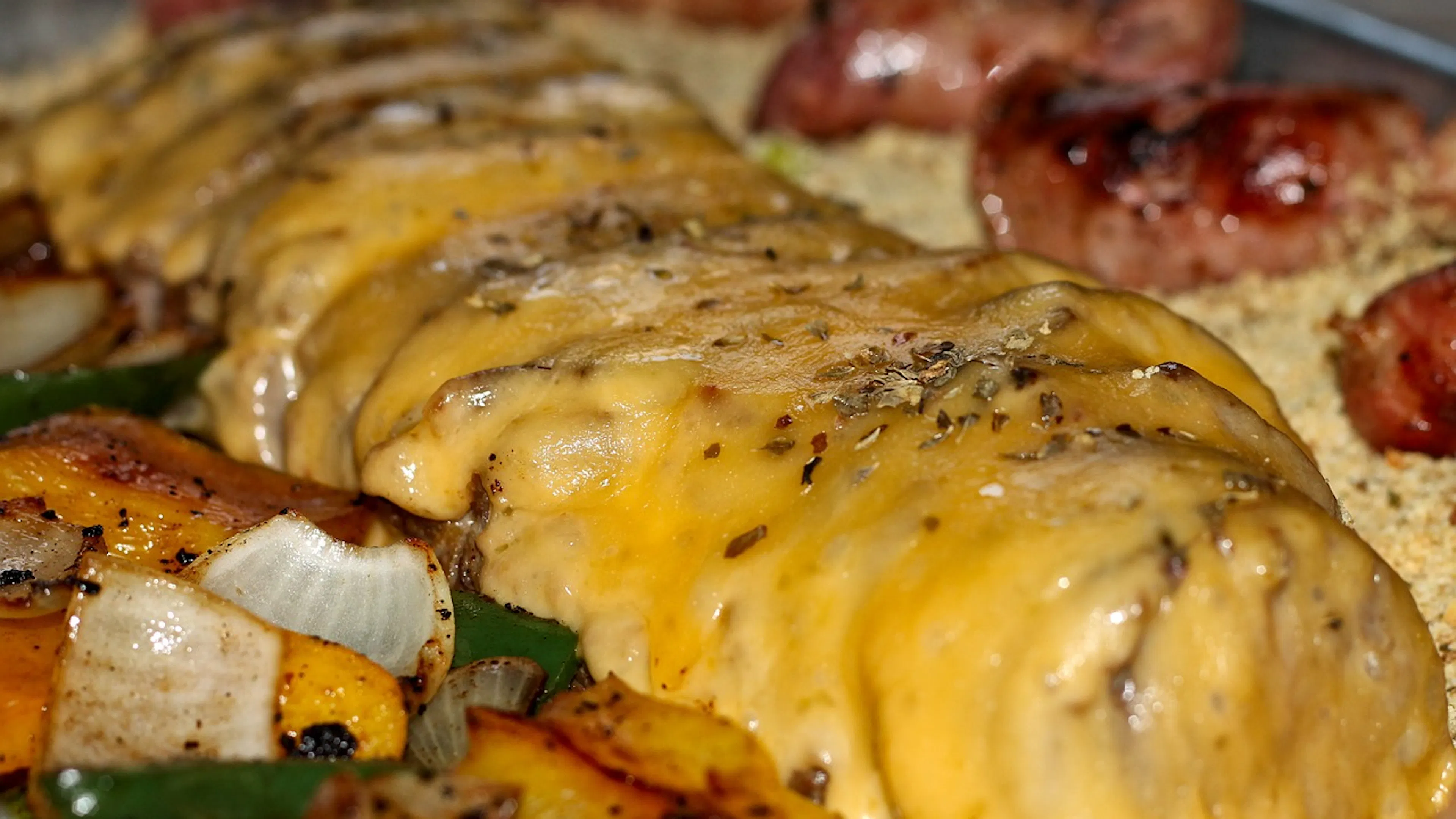 A close up of grilled steak strips coated in cheese beside sauteed peppers all atop a warm flour tortilla