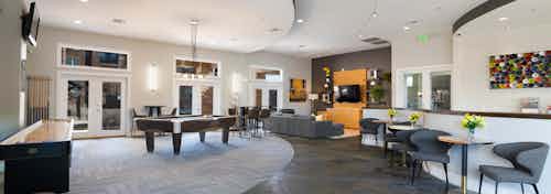 Interior view of the club room at AMLI Inverness apartments with a pool table and shuffle board and multiple seating areas