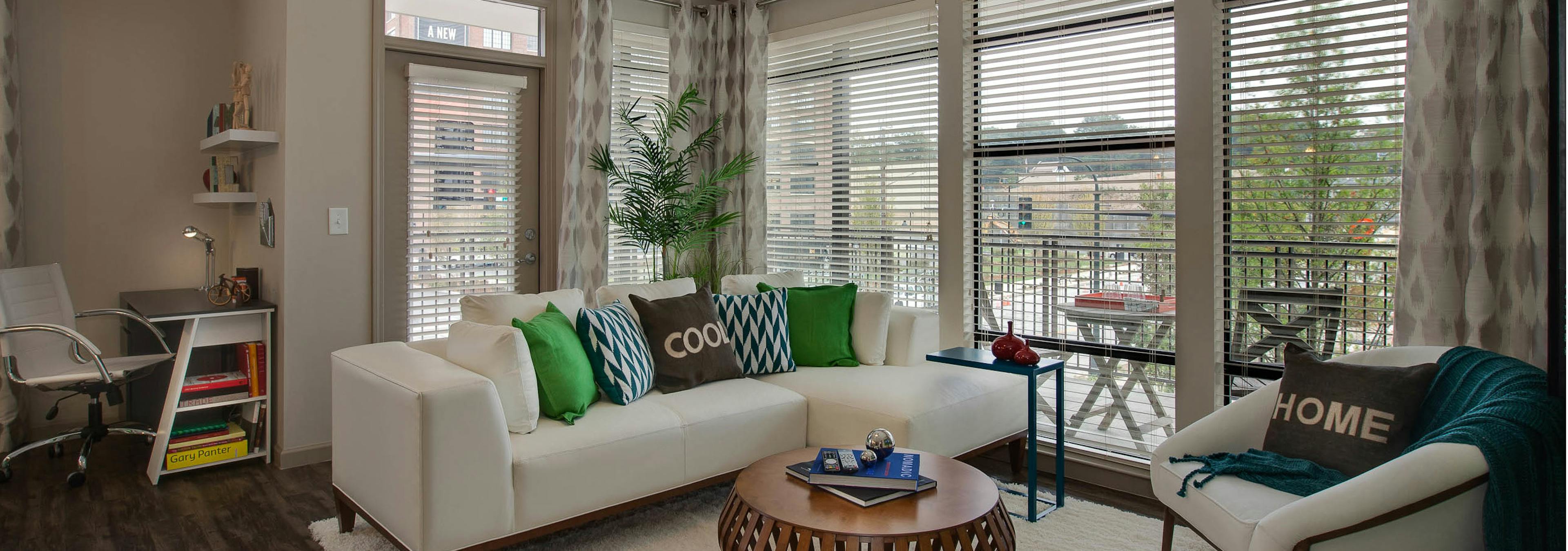 Apartment living room at AMLI Ponce Park with cream walls and dark hardwood with large windows letting in natural sunlight