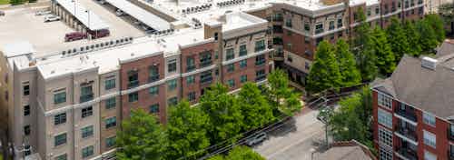 Daytime aerial view AMLI Uptown apartment building brick facade with trees in front and Houston skyline in the distance