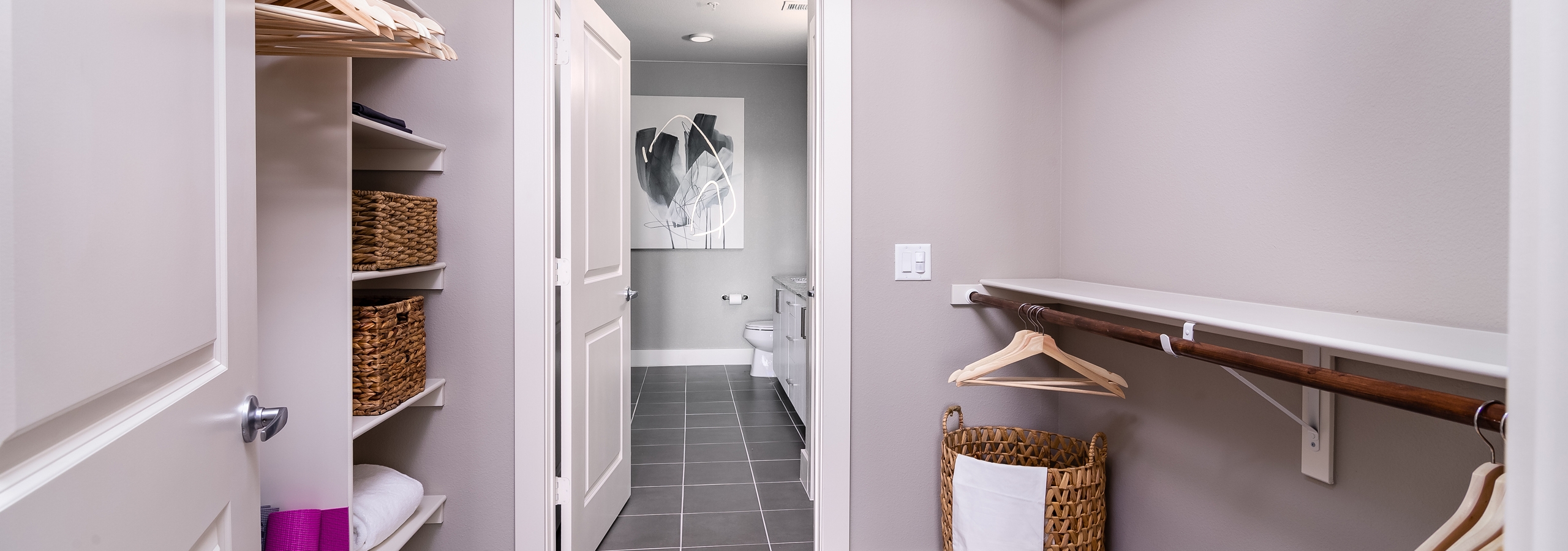 Interior of AMLI Littleton Village apartment’s walk-in closet with shelving, wicker laundry hamper and peek into bathroom