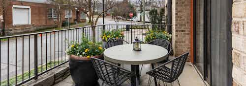 AMLI Old 4th Ward apartment patio showcasing patio table and chairs with flowers and a sliding glass door to the living room