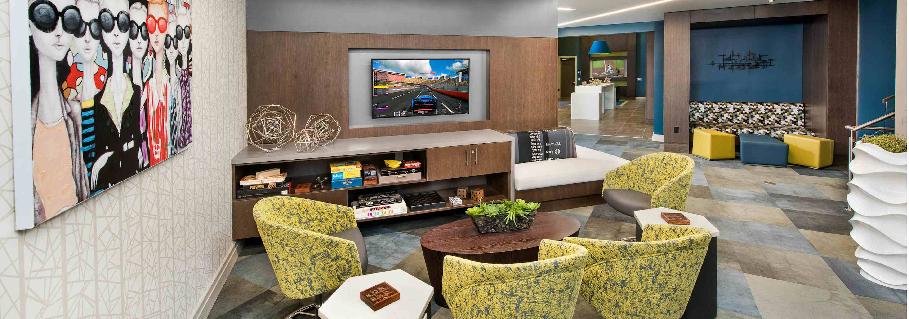 Clubroom at AMLI Buckhead with patterned yellow chairs and an entertainment center with a flat screen TV hanging above it