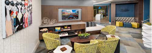 Clubroom at AMLI Buckhead with patterned yellow chairs and an entertainment center with a flat screen TV hanging above it