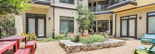 Close up of raised garden in the courtyard at AMLI 5350 with green leaves blooming and building facade in the background