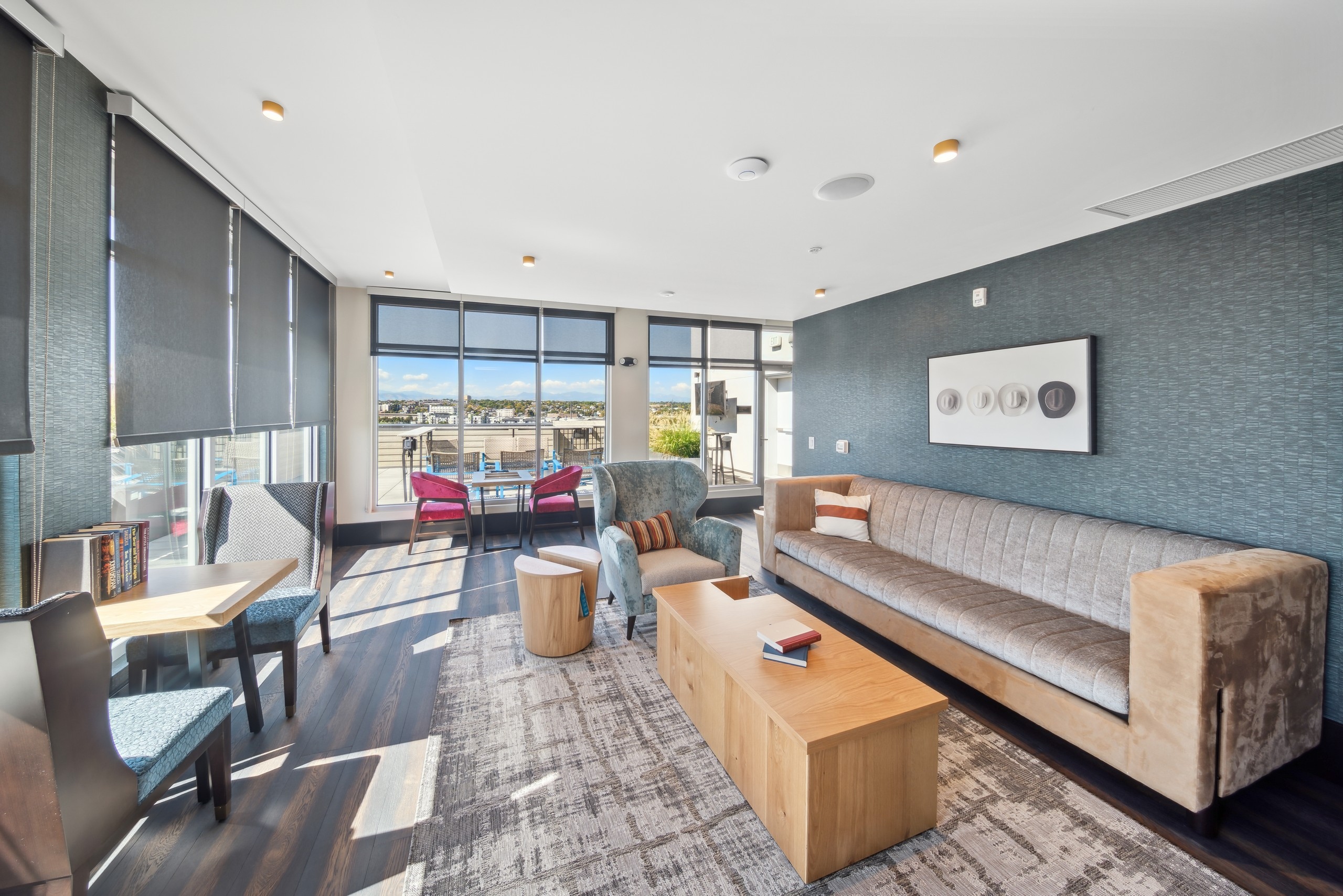 Lounge at AMLI RiNo with blue accent wall and tan couch and tables and chairs and view to the exterior patio area