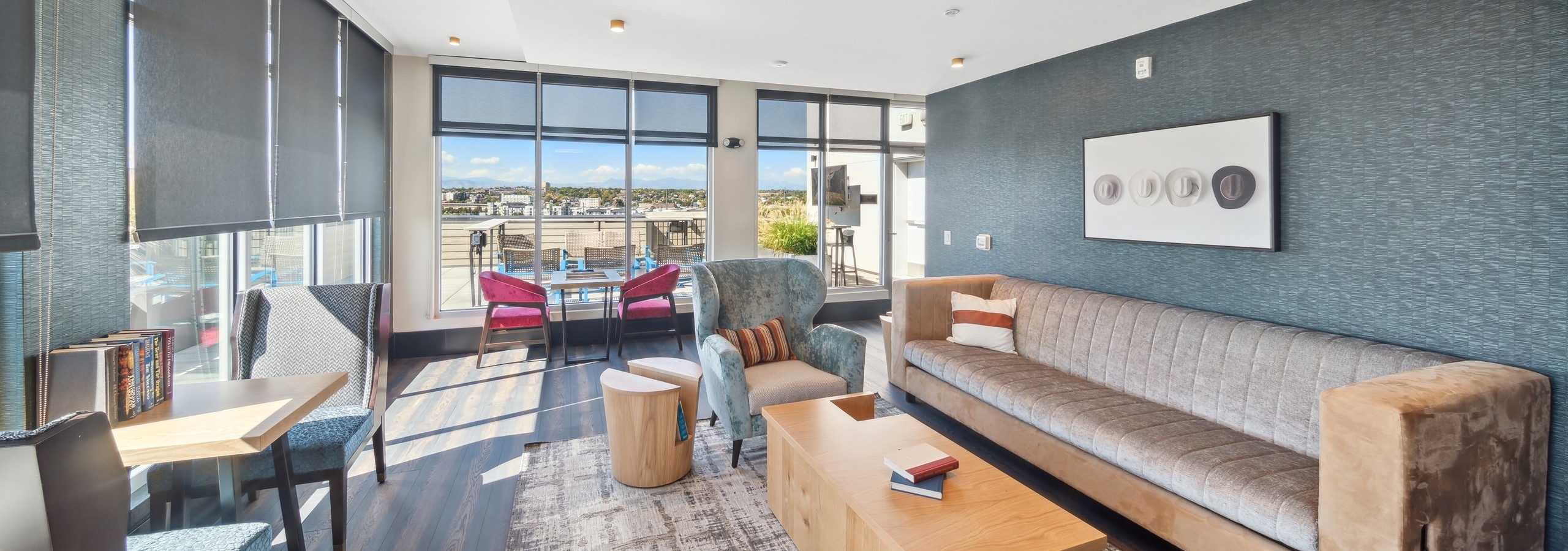 Lounge at AMLI RiNo with blue accent wall and tan couch and tables and chairs and view to the exterior patio area