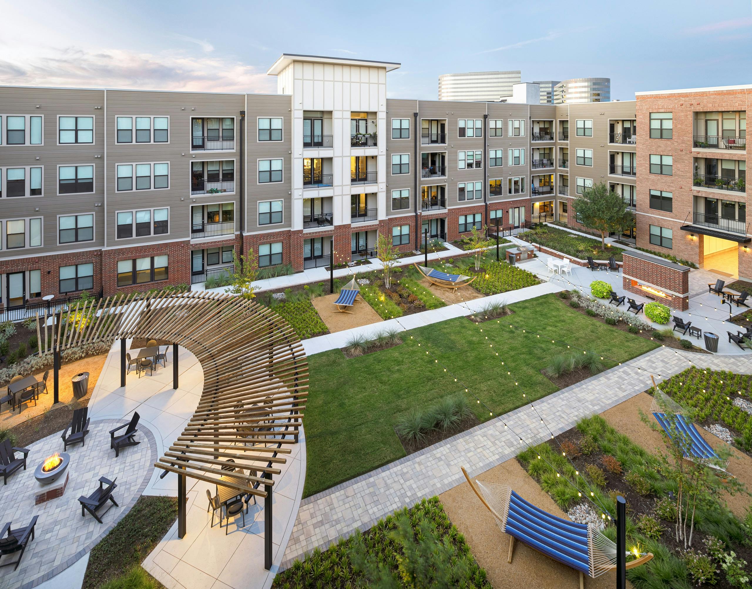 Aerial view of AMLI Addison lushly landscaped courtyard with string lights and hammocks and pergola and seating throughout