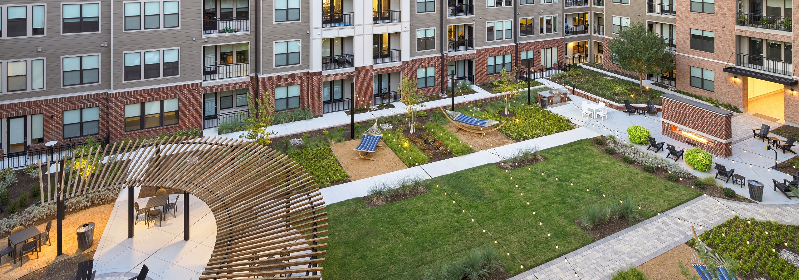 Aerial view of AMLI Addison lushly landscaped courtyard with string lights and hammocks and pergola and seating throughout